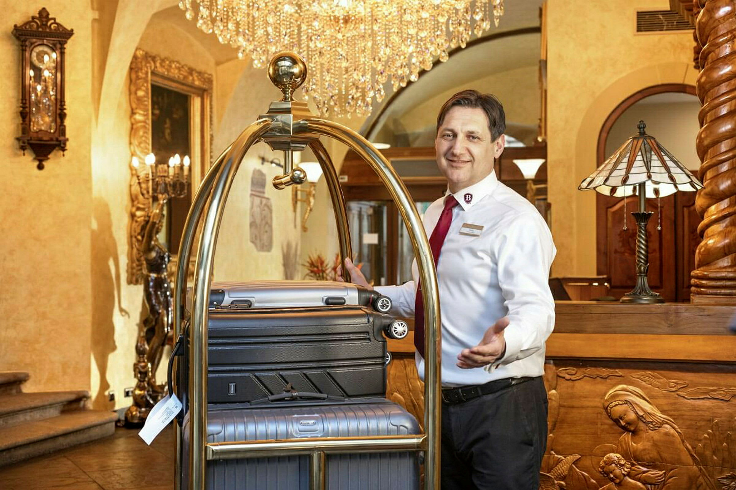 En hotellansatt ved en resepsjon med kofferter på en bagasjetralle. (AI-generert tekst)