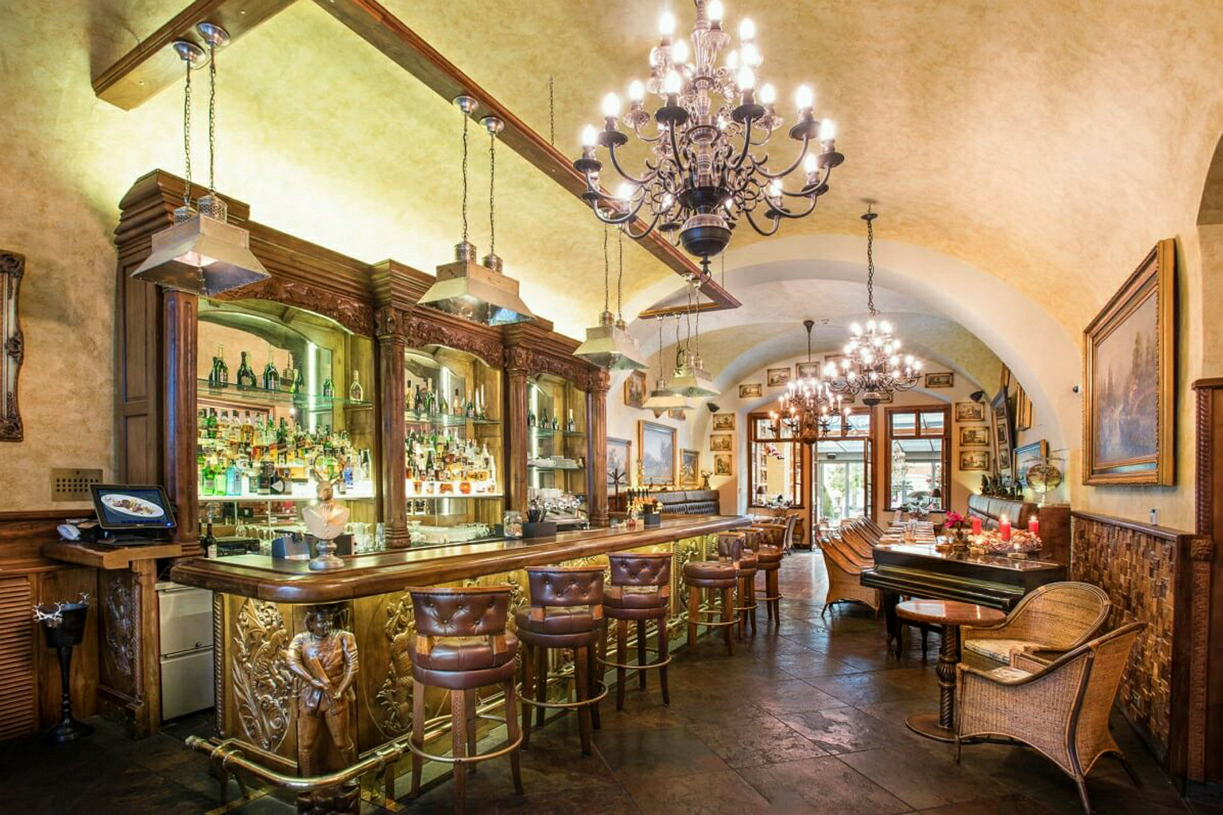Et elegant interiør av en bar med luksuriøse møbler, taklamper og en velutstyrt bar. (AI-generert tekst)