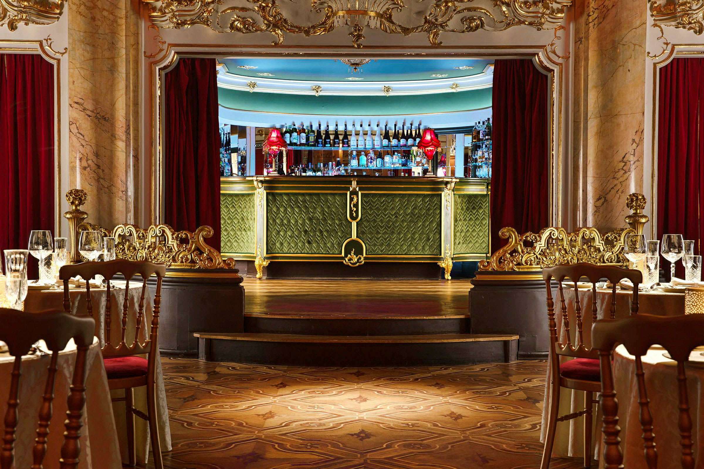 En luksuriøs bar med grønn dekor og gulldetaljer. Foran baren er et elegant spiseområde med dekkede bord. (AI-generert tekst)