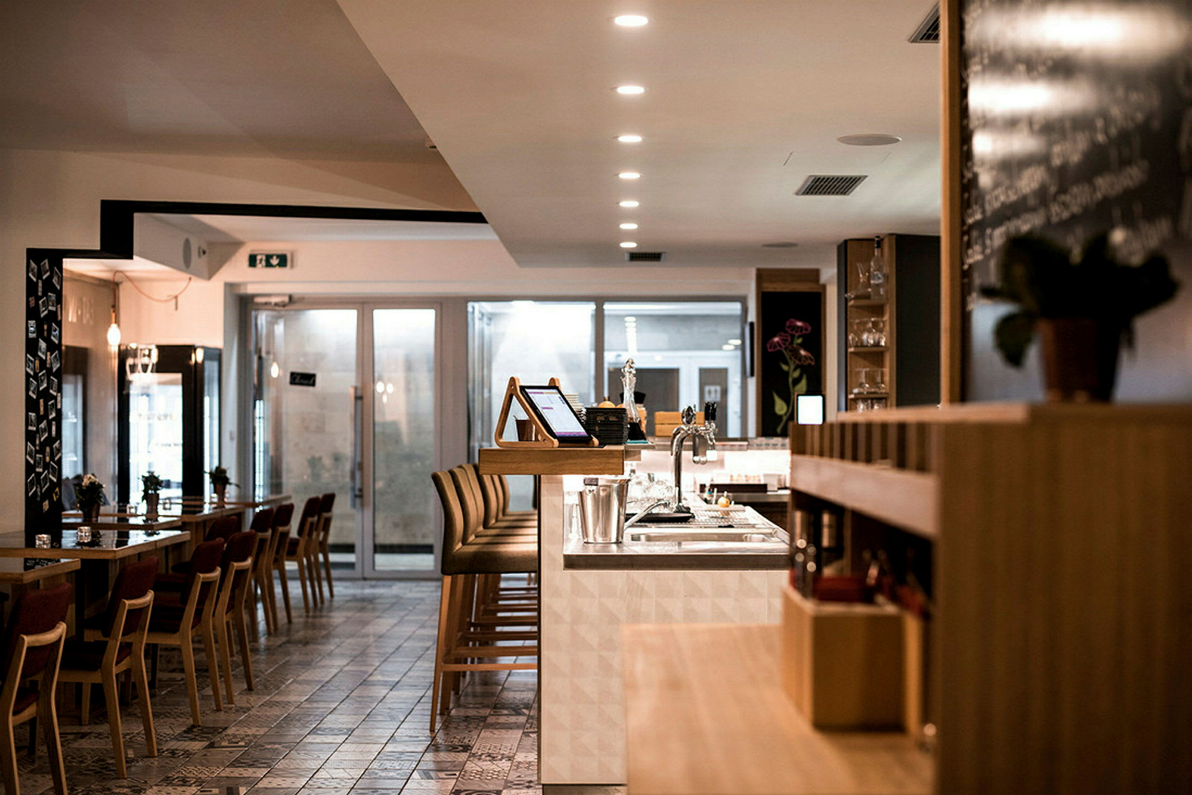 Interiør av en moderne restaurant med bord, stoler og en bardisk. (AI-generert tekst)