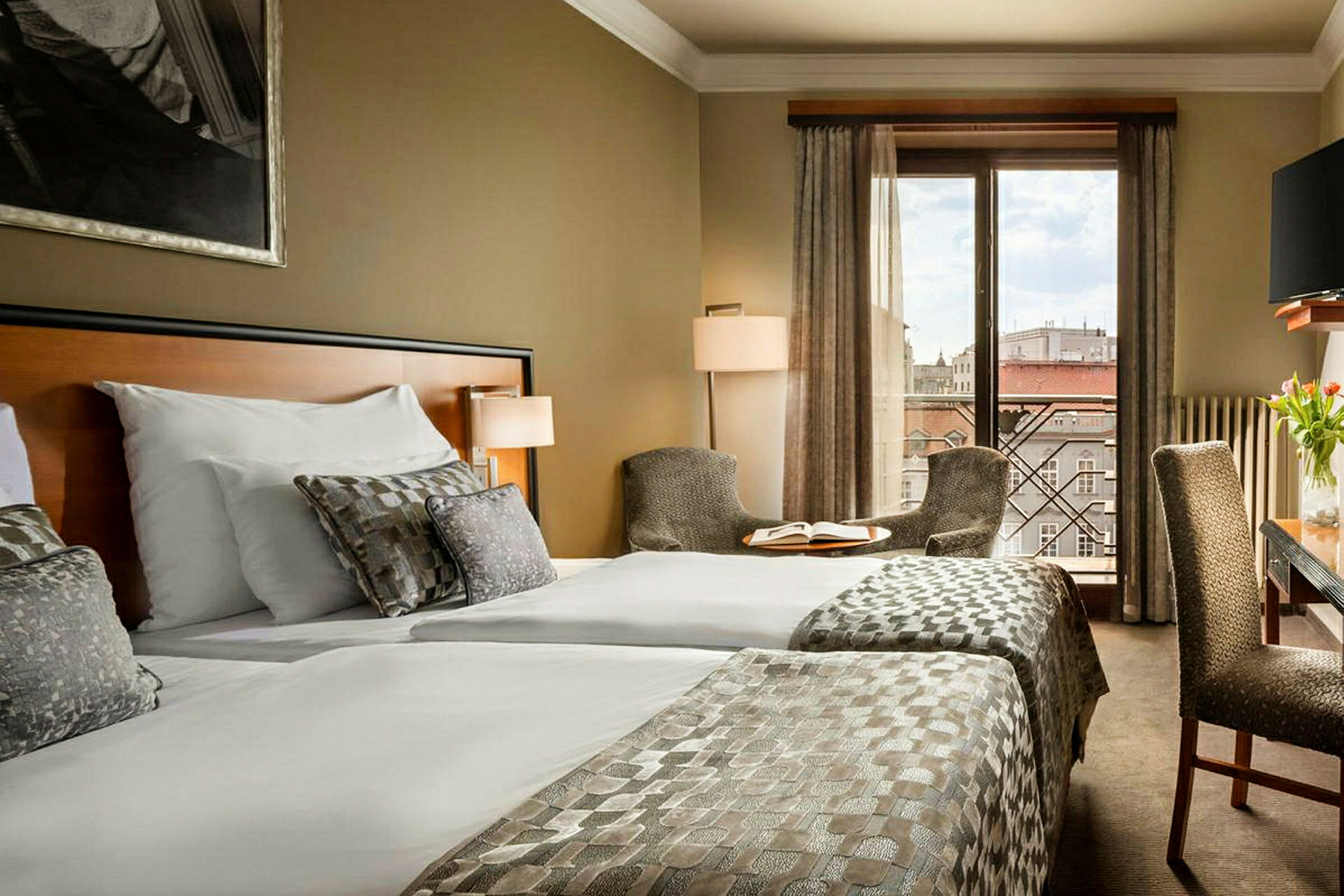 Hotellrom med to senger, sitteplasser og utsikt over byen. (AI-generert tekst)