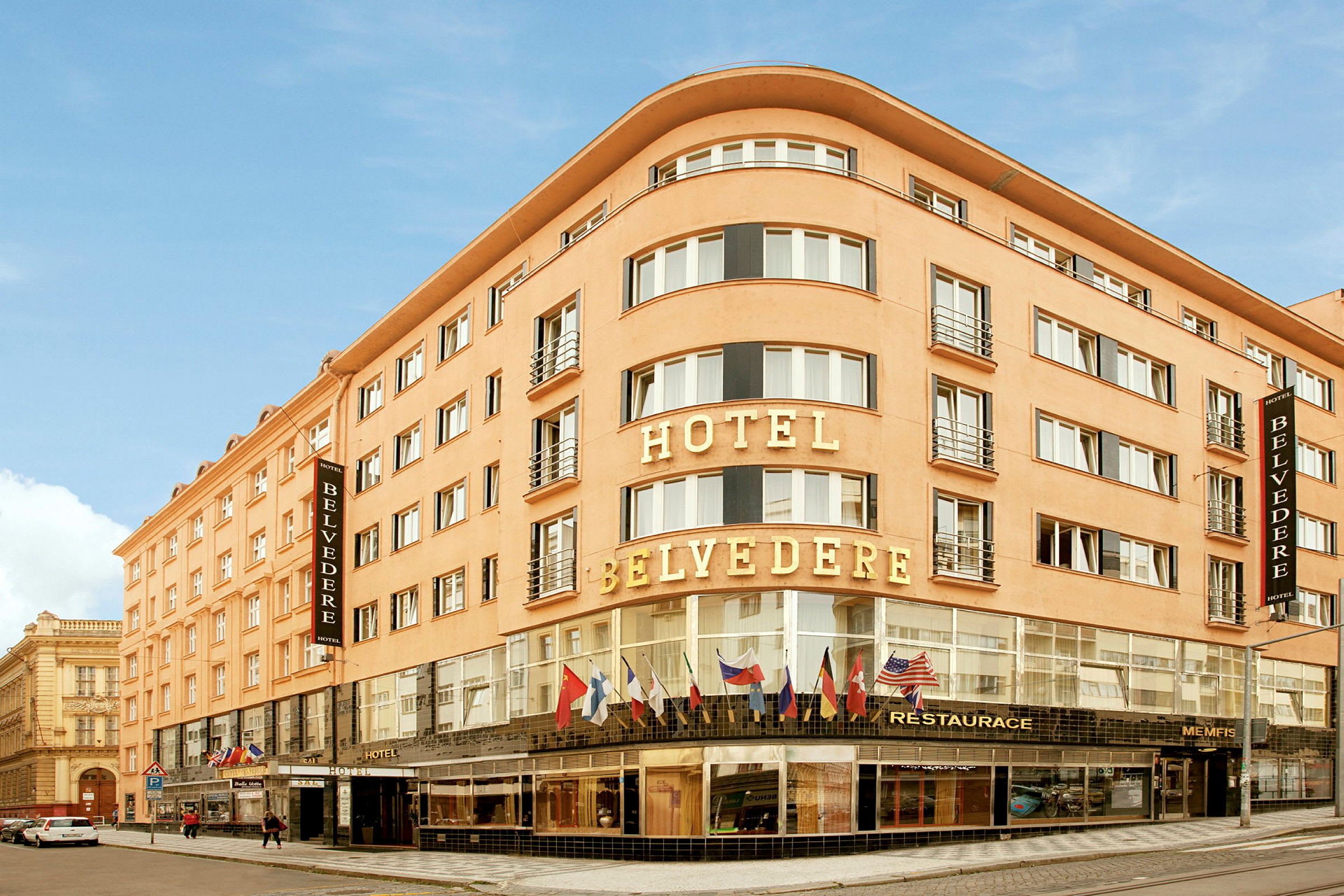 Et hotell med navnet Hotel Belvedere, en bygning med flere etasjer og glassvinduer med flagg over inngangen. (AI-generert tekst)