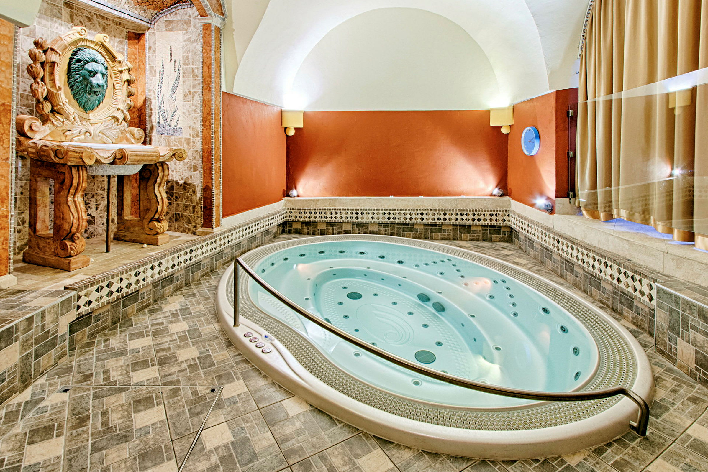En innendørs jacuzzi med mosaikk og dekorativ ornamentering på vegger og gulv. (AI-generert tekst)