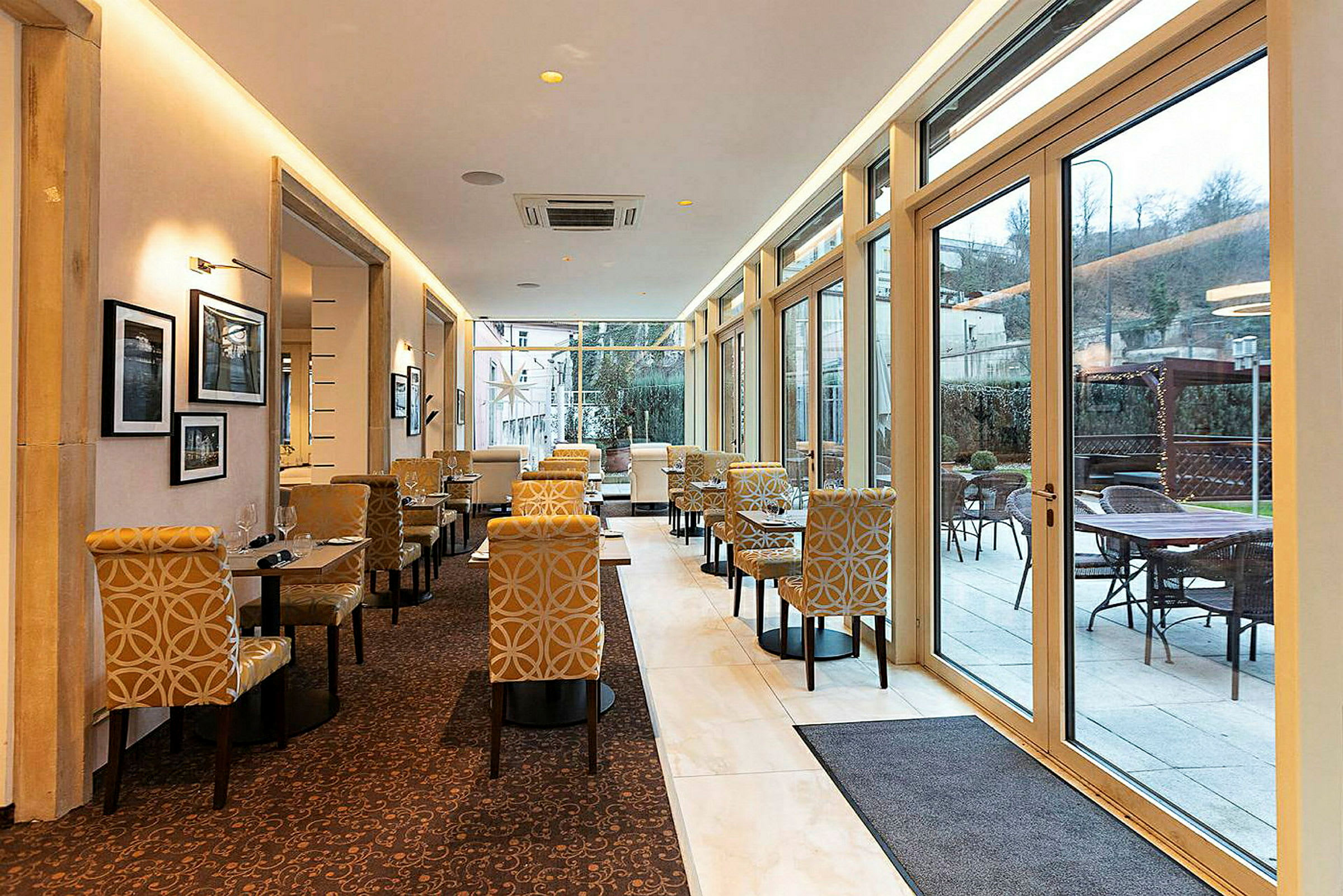 Bilde av en restaurant eller kafé med elegante møbler og store vinduer som slipper inn rikelig med lys. (AI-generert tekst)
