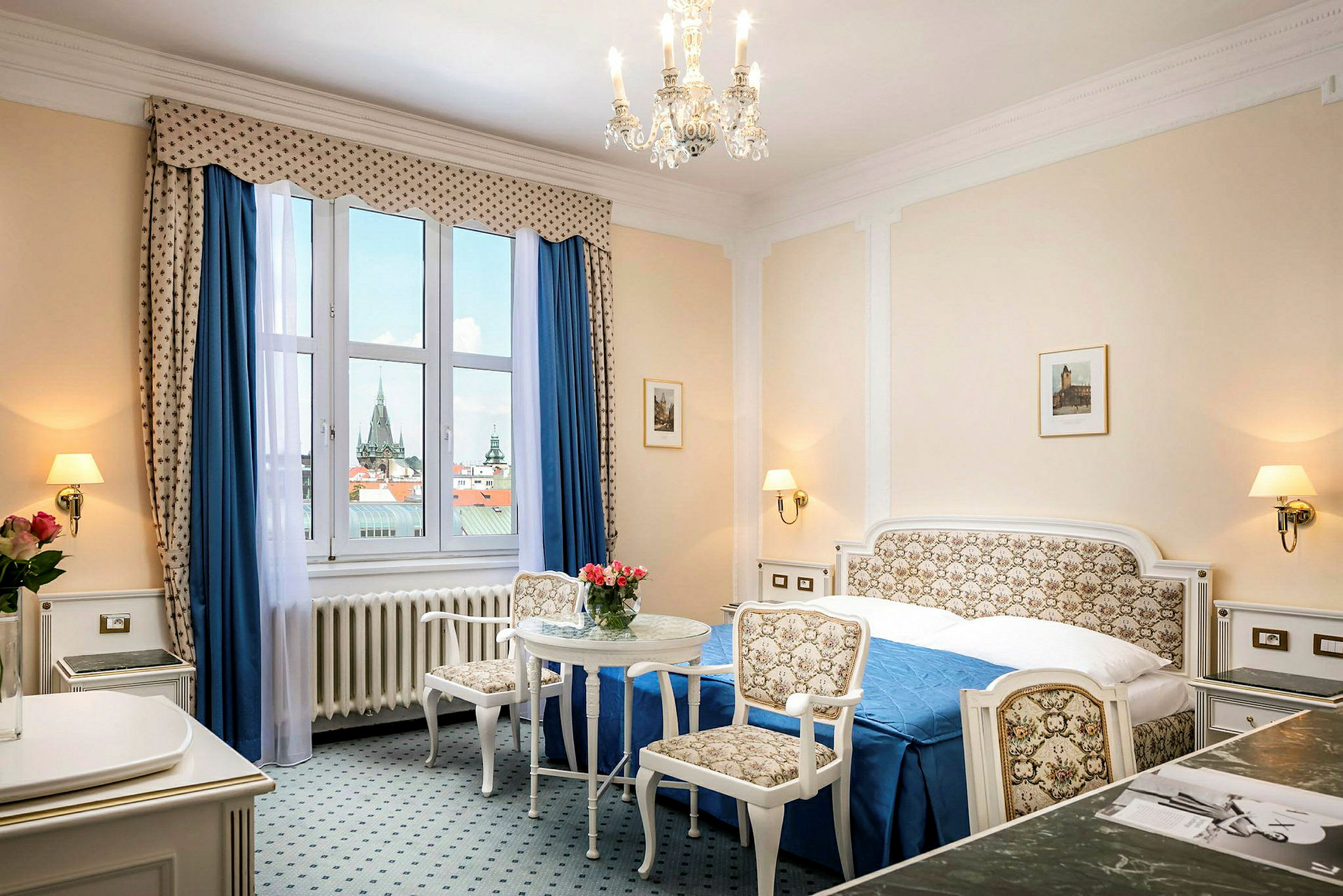 Et hotellrom med klassisk innredning, en dobbeltseng, to stoler og et bord samt en stor vindusutstilling. (AI-generert tekst)