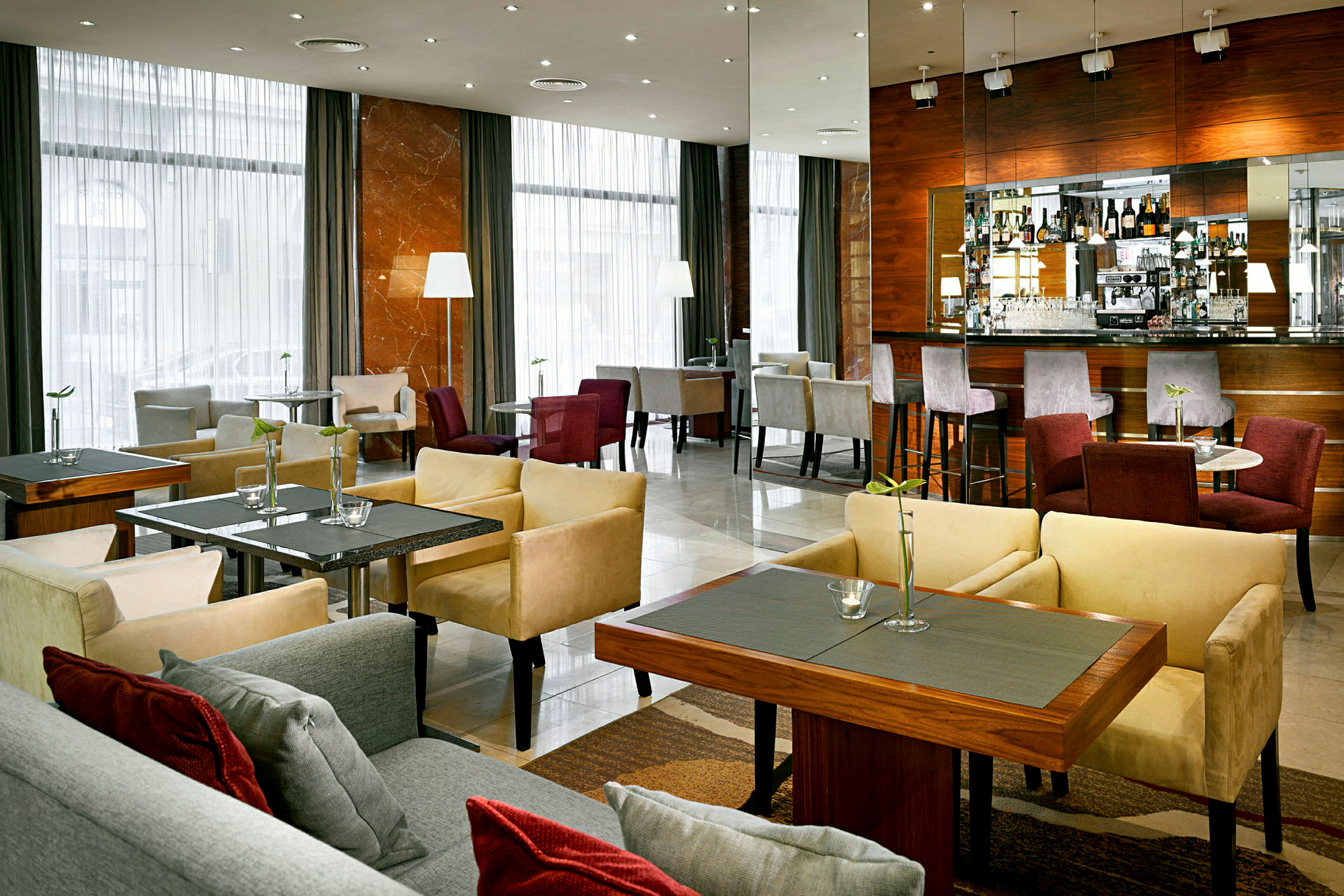 En moderne hotellbar med sittemøbler og bord samt en bardisk med stoler. (AI-generert tekst)