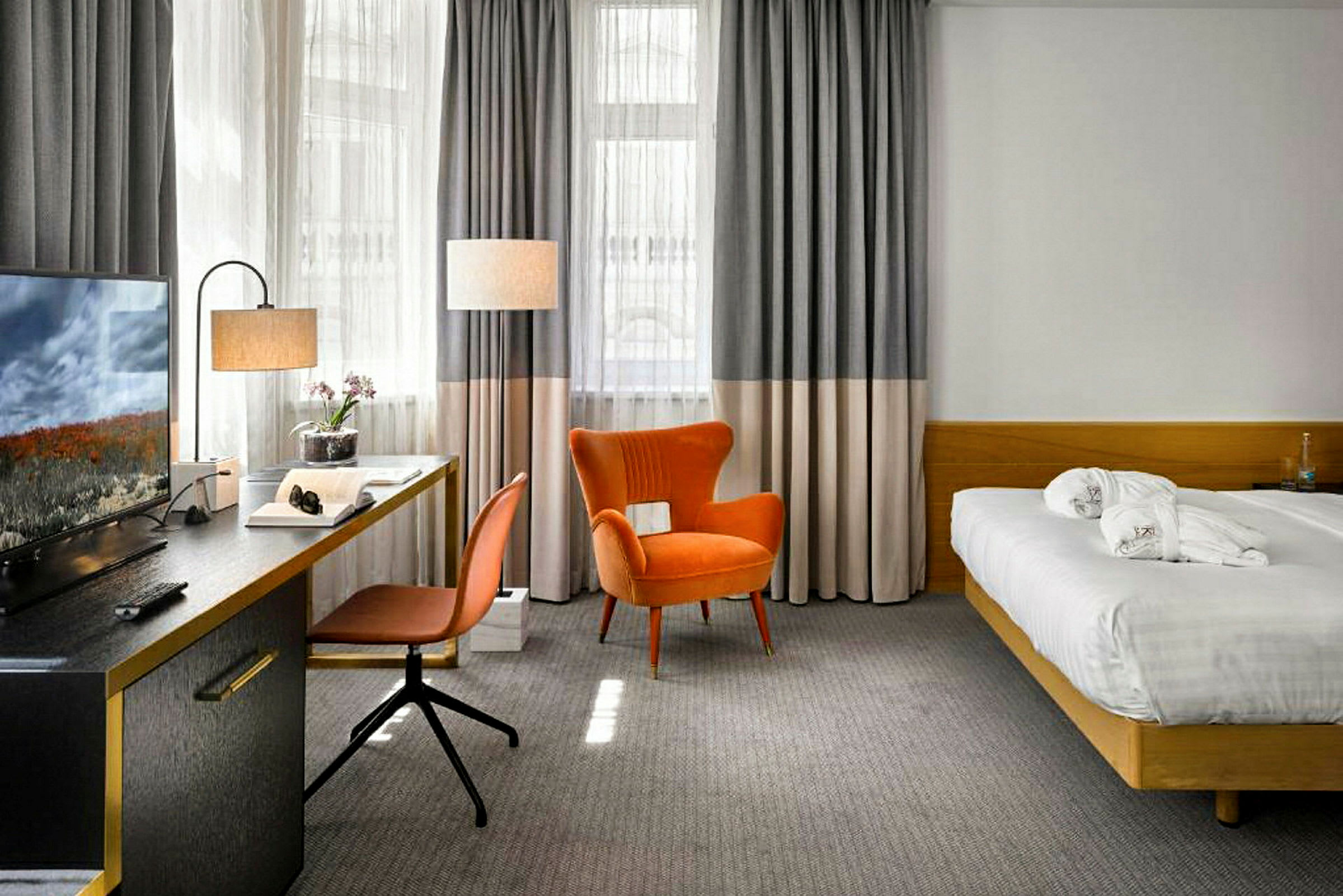 Et hotellrom med en seng, skrivebord, stol og lenestol. (AI-generert tekst)