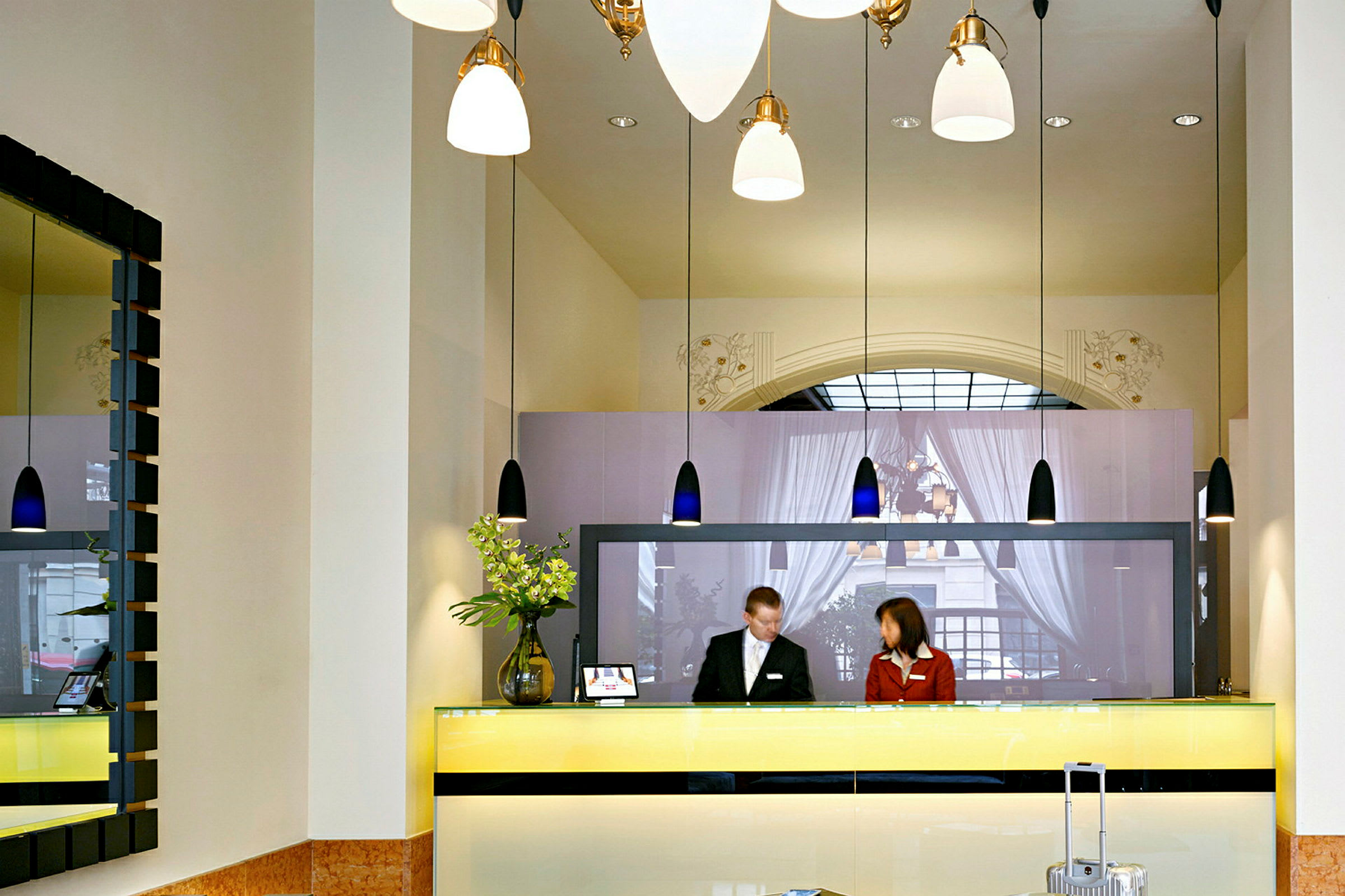 Resepsjon med to personer bak en gul disk i en hotellobby. (AI-generert tekst)