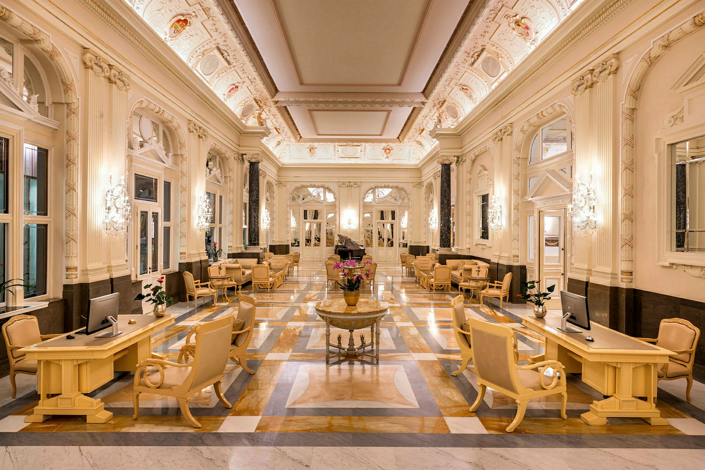 En elegant hotellobby med marmorgulv, stilfulle møbler og dekorativt utsmykket takpanel. (AI-generert tekst)