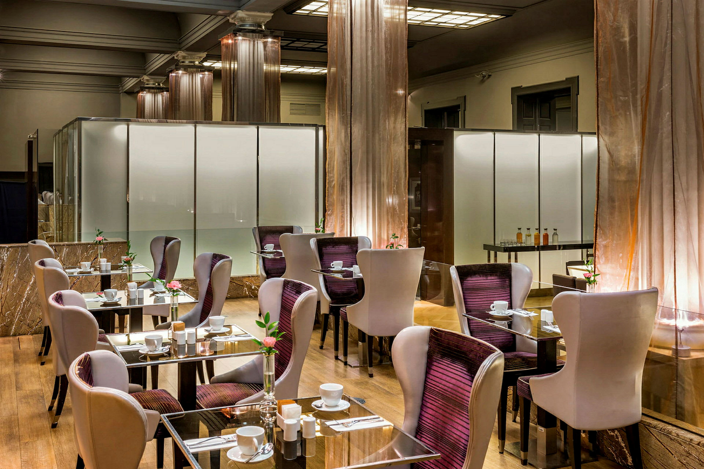 Moderne restaurant med bord og stoler. Glassbord med borddekking og blomsterdekorasjoner. (AI-generert tekst)
