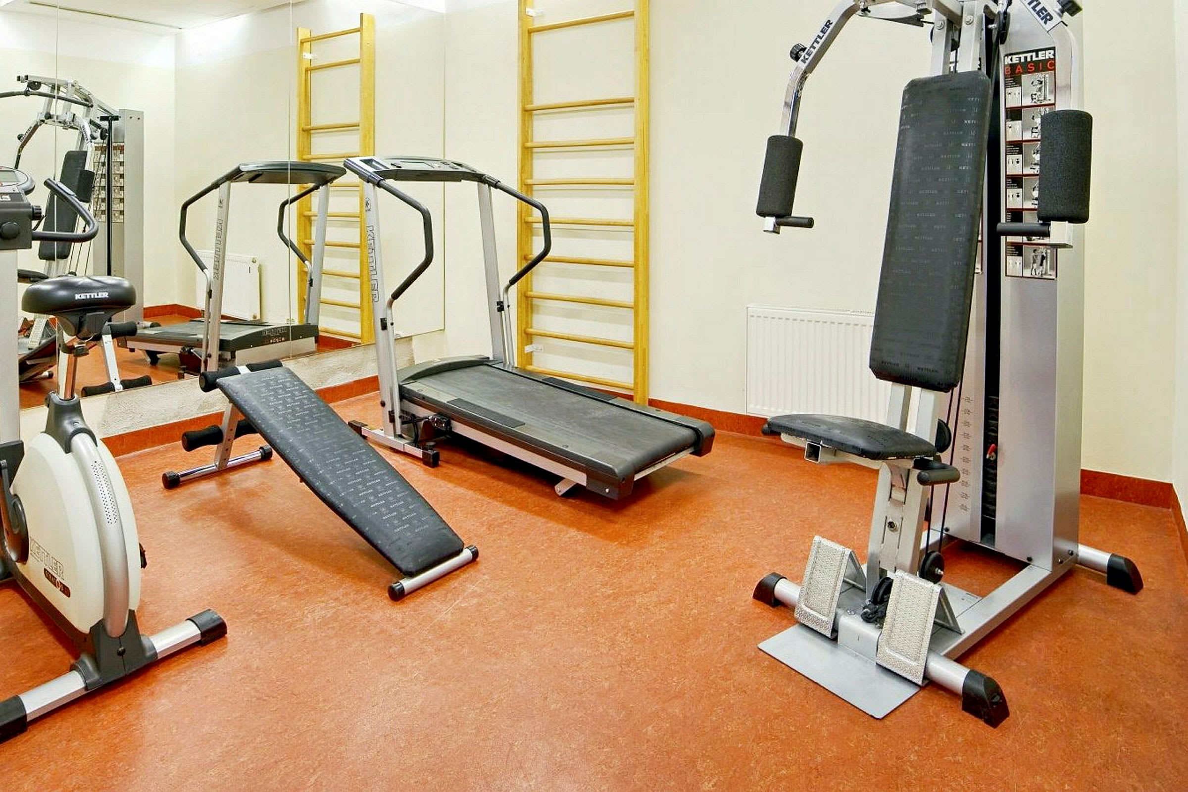 Bilde av et treningsstudio med ulike treningsmaskiner, inkludert en tredemølle, en treningssykkel og en multifunksjonell treningsmaskin. (AI-generert tekst)