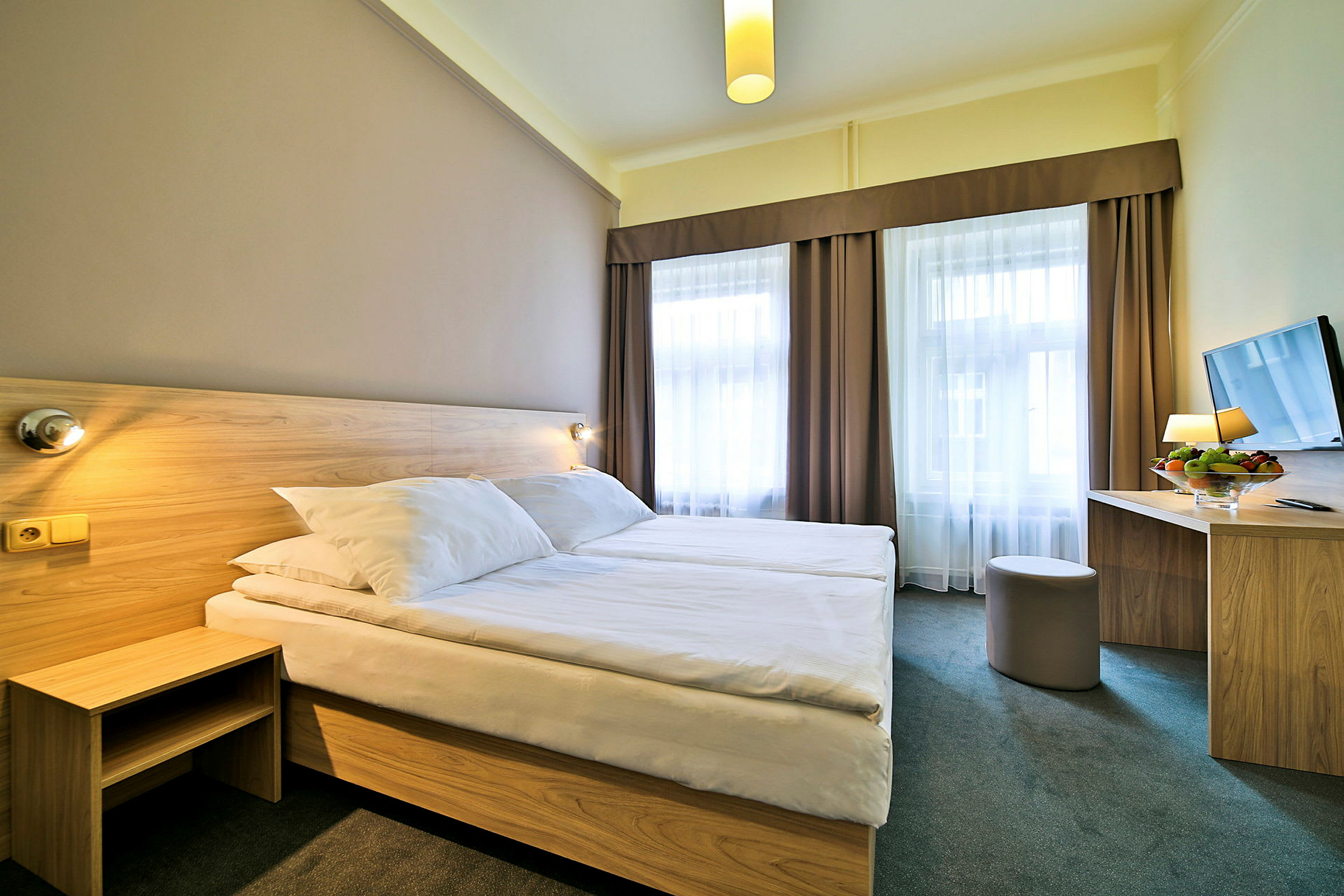Et hotellrom med to enkeltsenger og et bord med en stol. (AI-generert tekst)