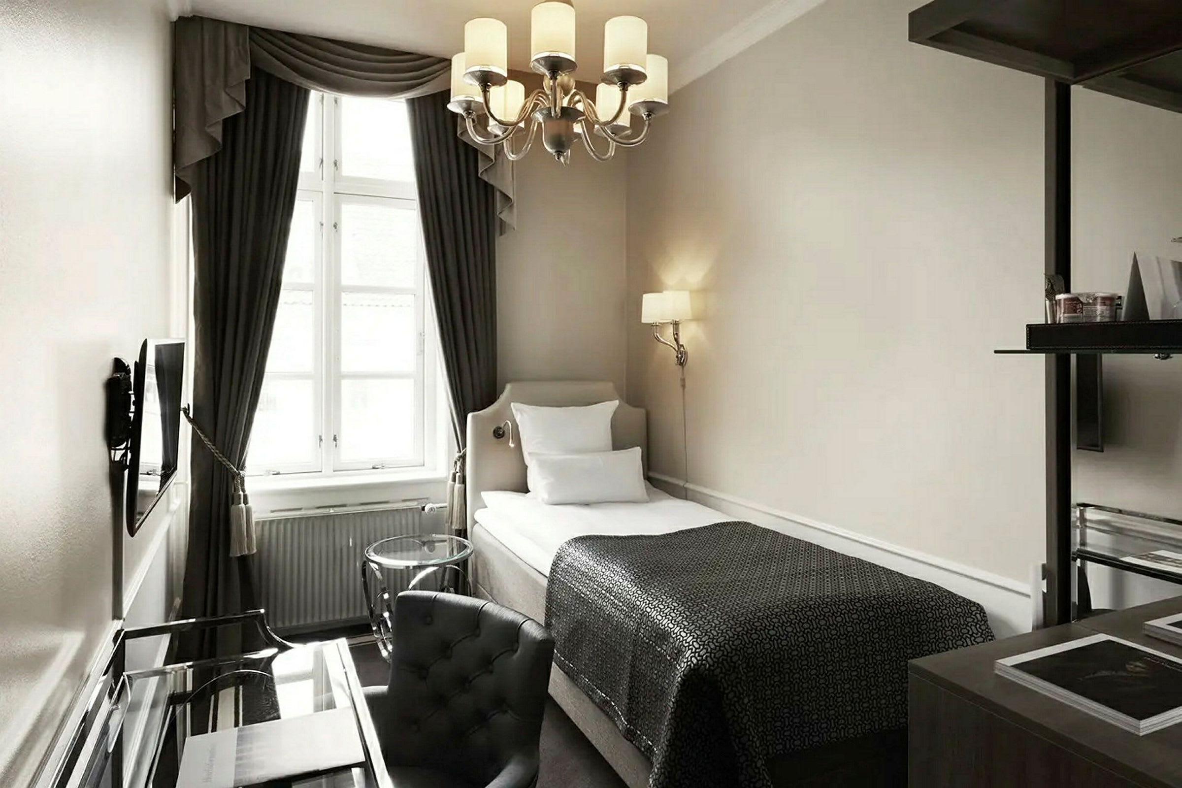 Et elegant innredet hotellrom med en enkeltseng, et skrivebord og en lenestol. (AI-generert tekst)
