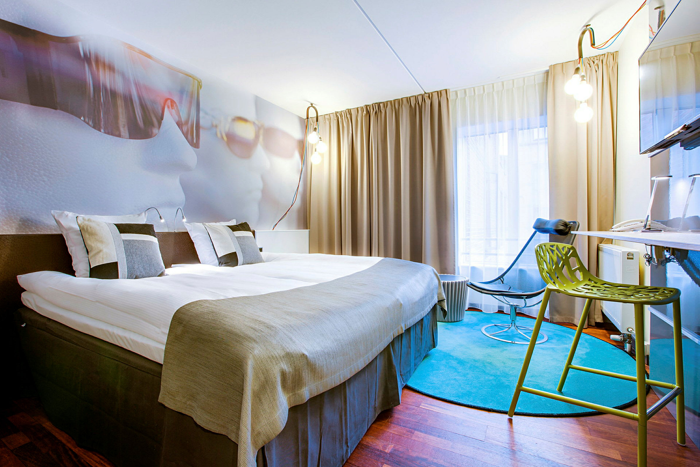 Et hotellrom med en stor seng, moderne møbler og et fargerikt teppe. (AI-generert tekst)