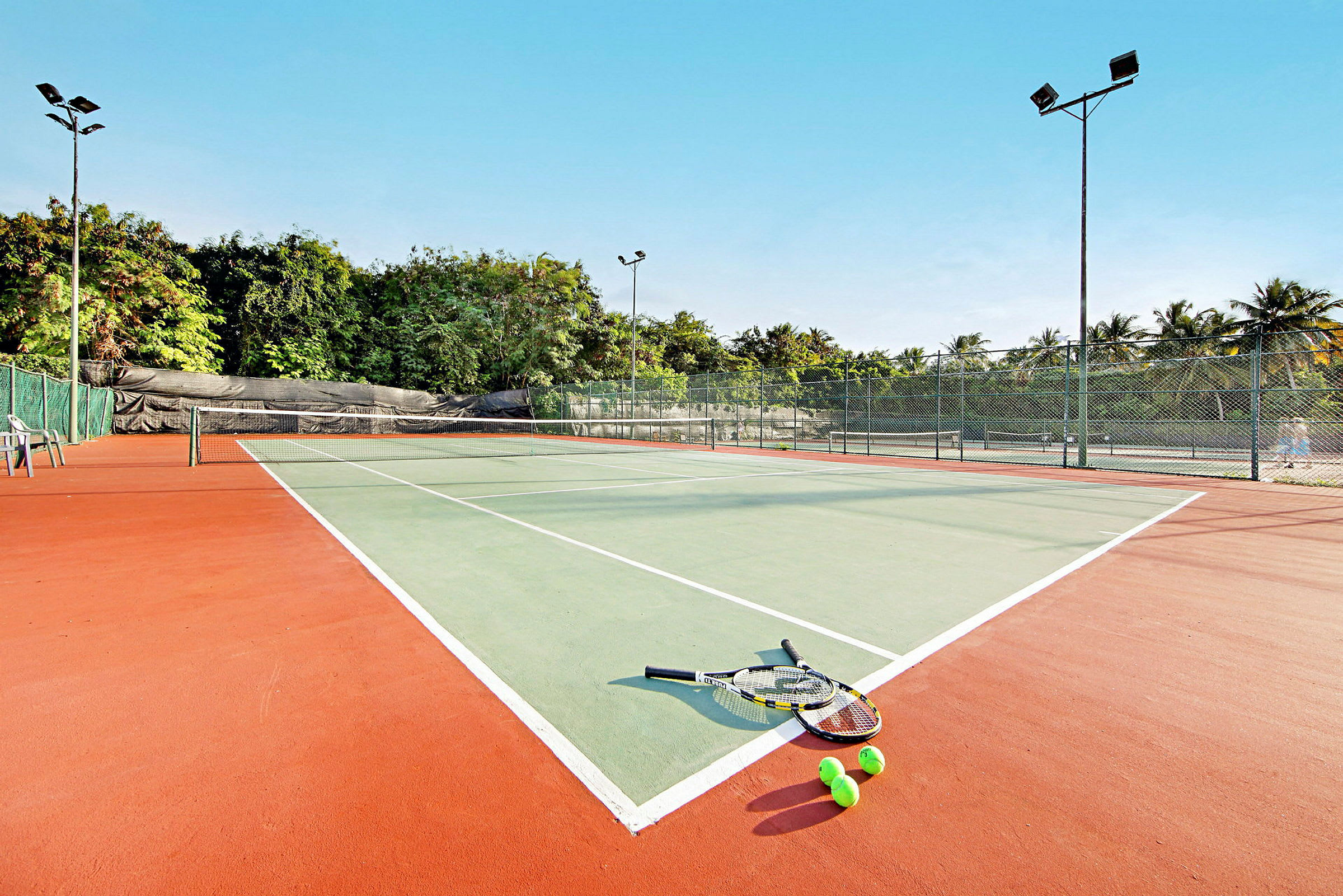 En tennisbane med racketer og baller som ligger på bakken. (AI-generert tekst)