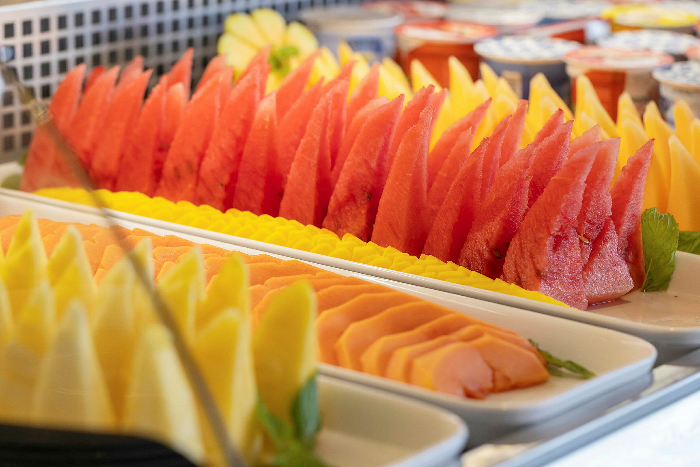 Oppskåret frukt som melon, papaya og ananas lagt opp på fat. (AI-generert tekst)