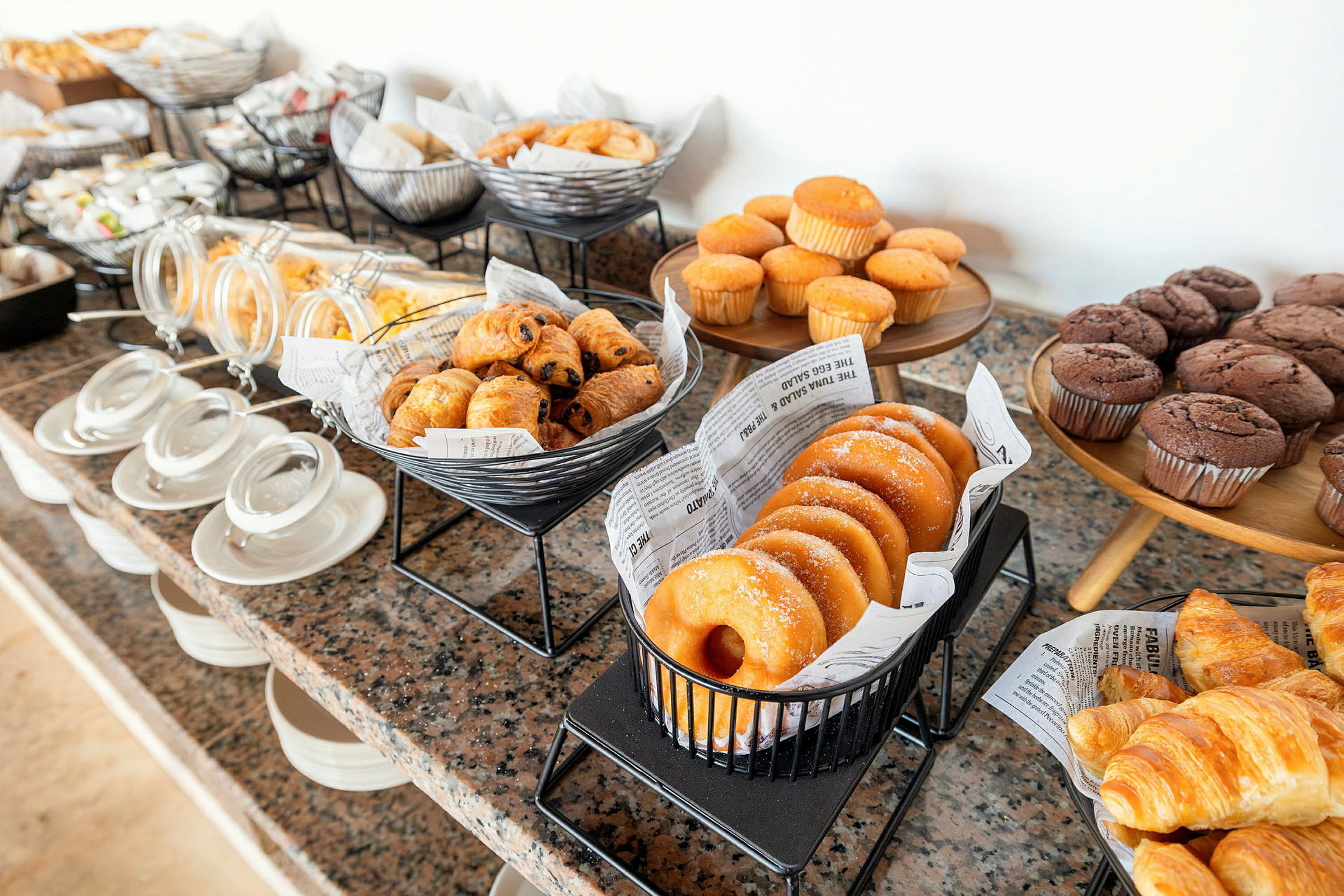 En buffet med forskjellige bakverk som muffins, croissanter og donuts. (AI-generert tekst)