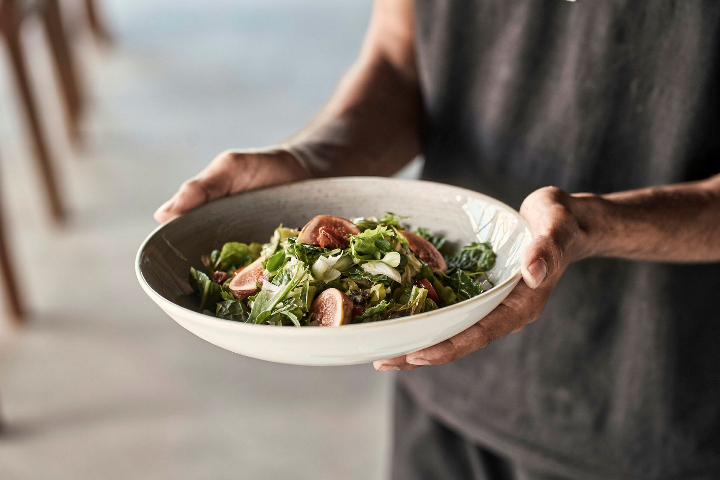 En person holder en skål med salat. (AI-generert tekst)