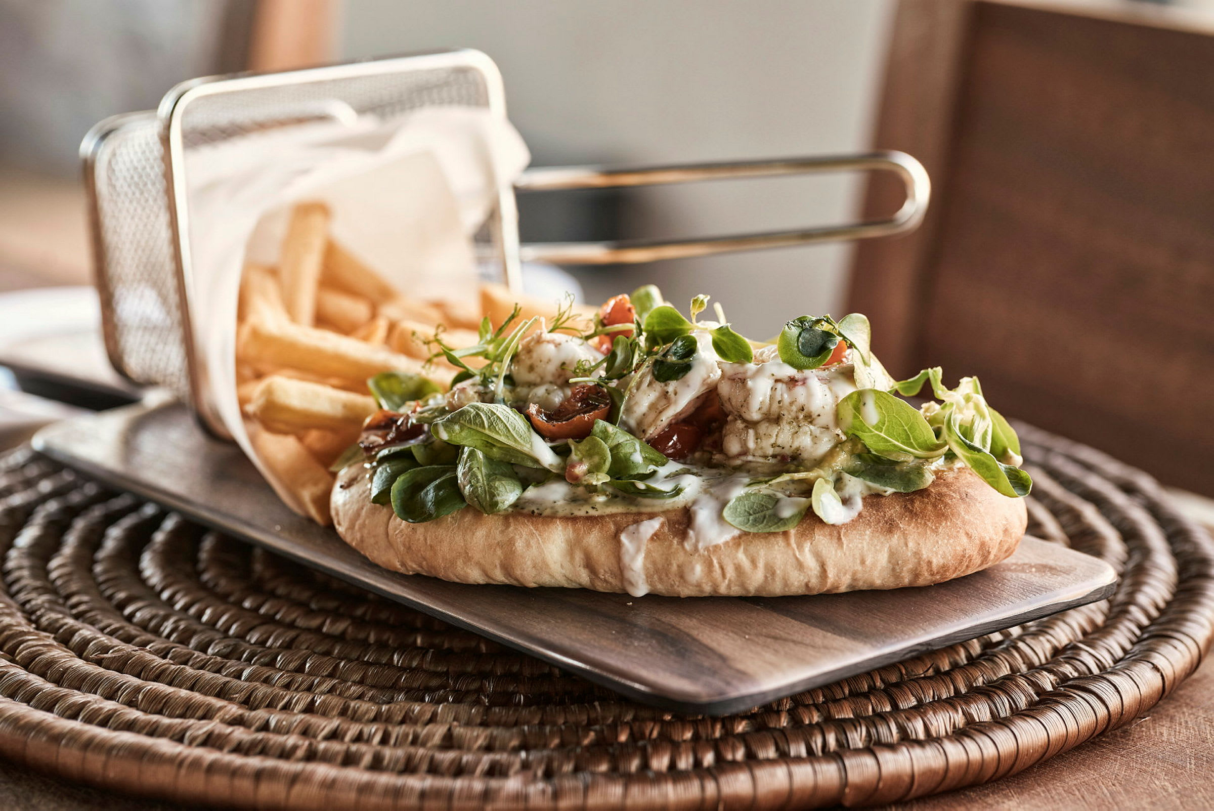 En tallerken med pommes frites og en flatbrødsandwich med grønt og dressing. (AI-generert tekst)