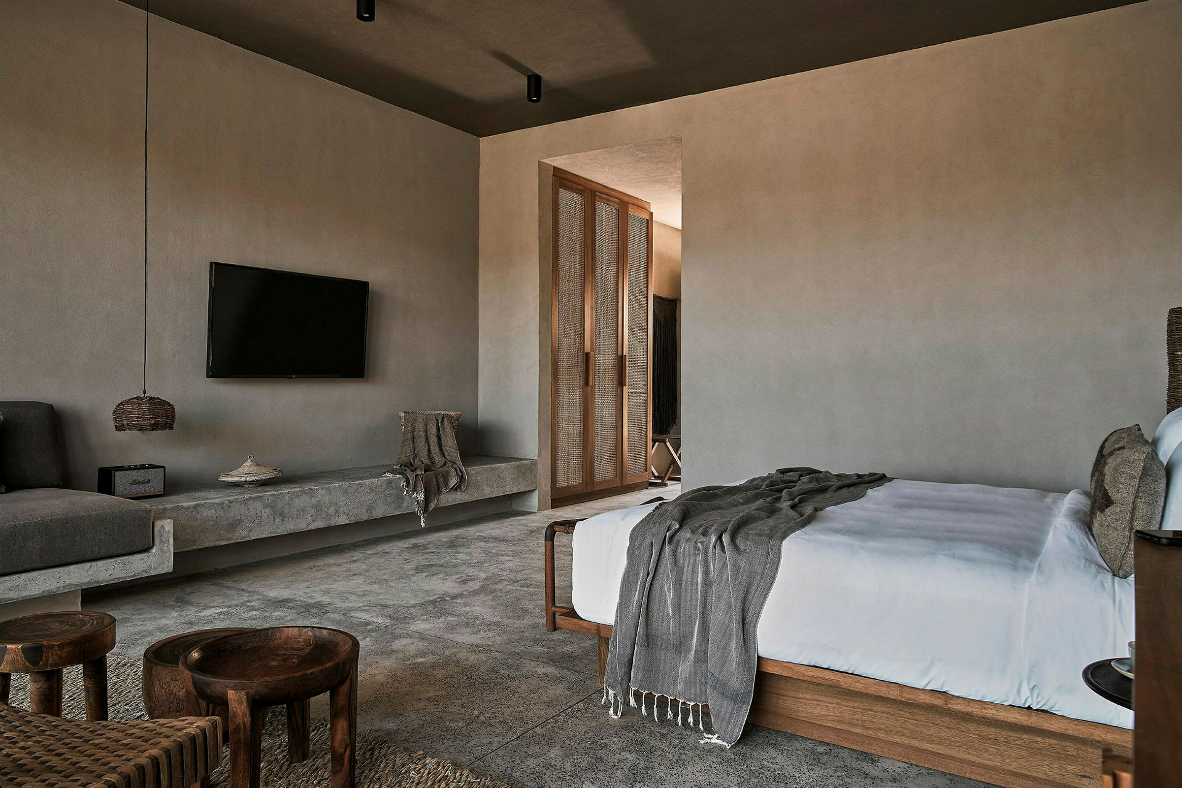 Et moderne designet hotellrom med TV, seng, sitteområde og inngang til en annen del av rommet. (AI-generert tekst)