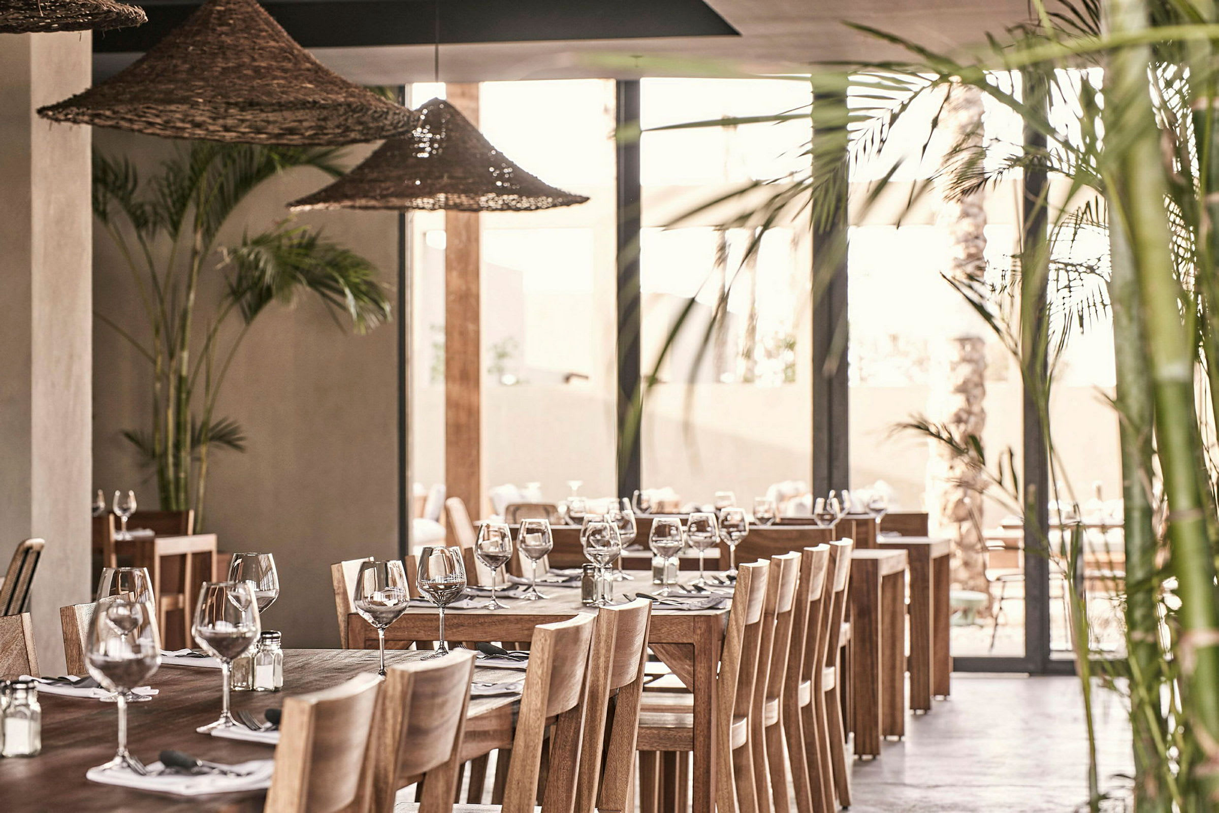 Interiør av en restaurant med trebord, stoler og dekorert med glass og bestikk. (AI-generert tekst)