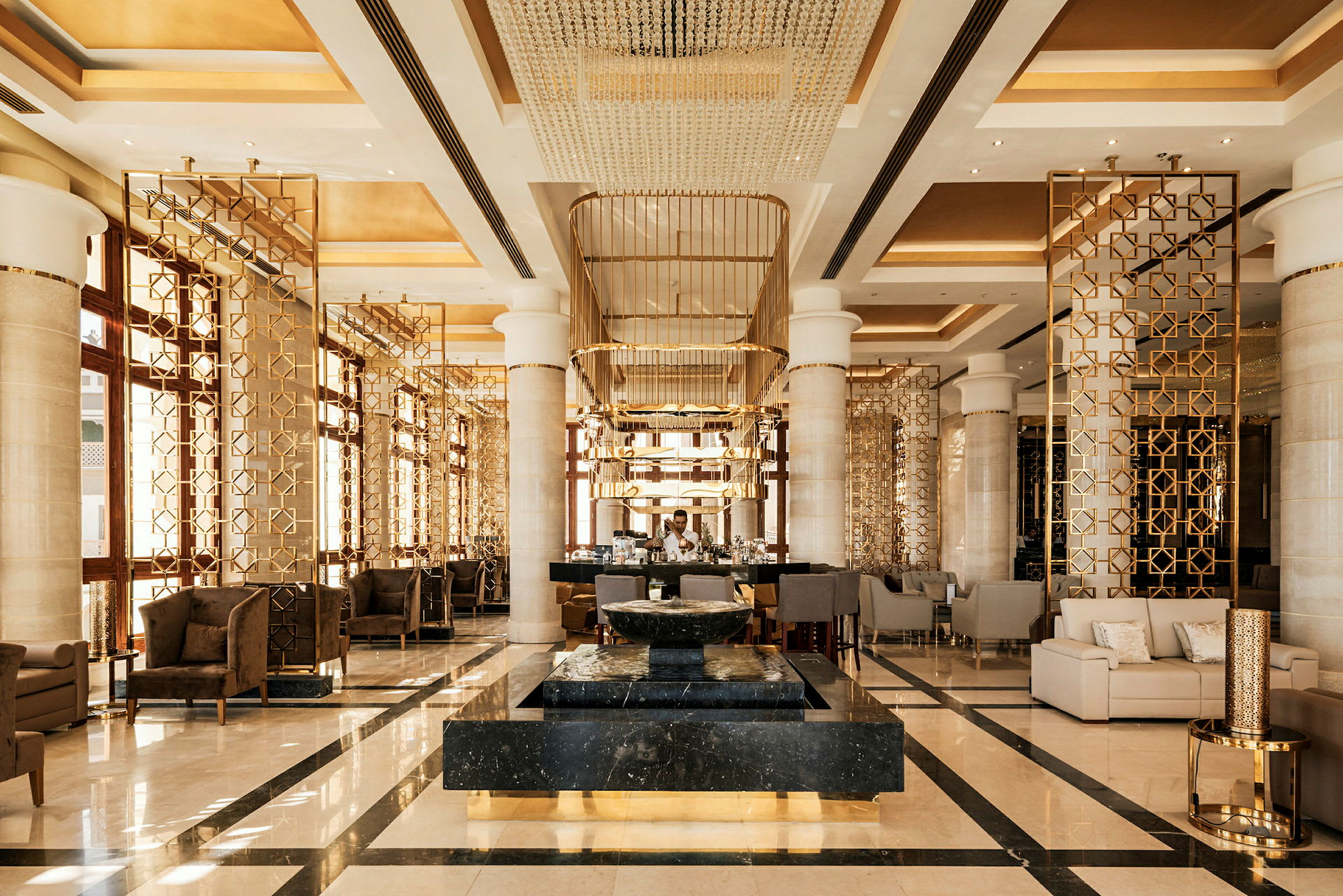 En elegant hotellobby med moderne møbler, gullfargede dekorasjoner og et marmordekorasjon i midten. (AI-generert tekst)