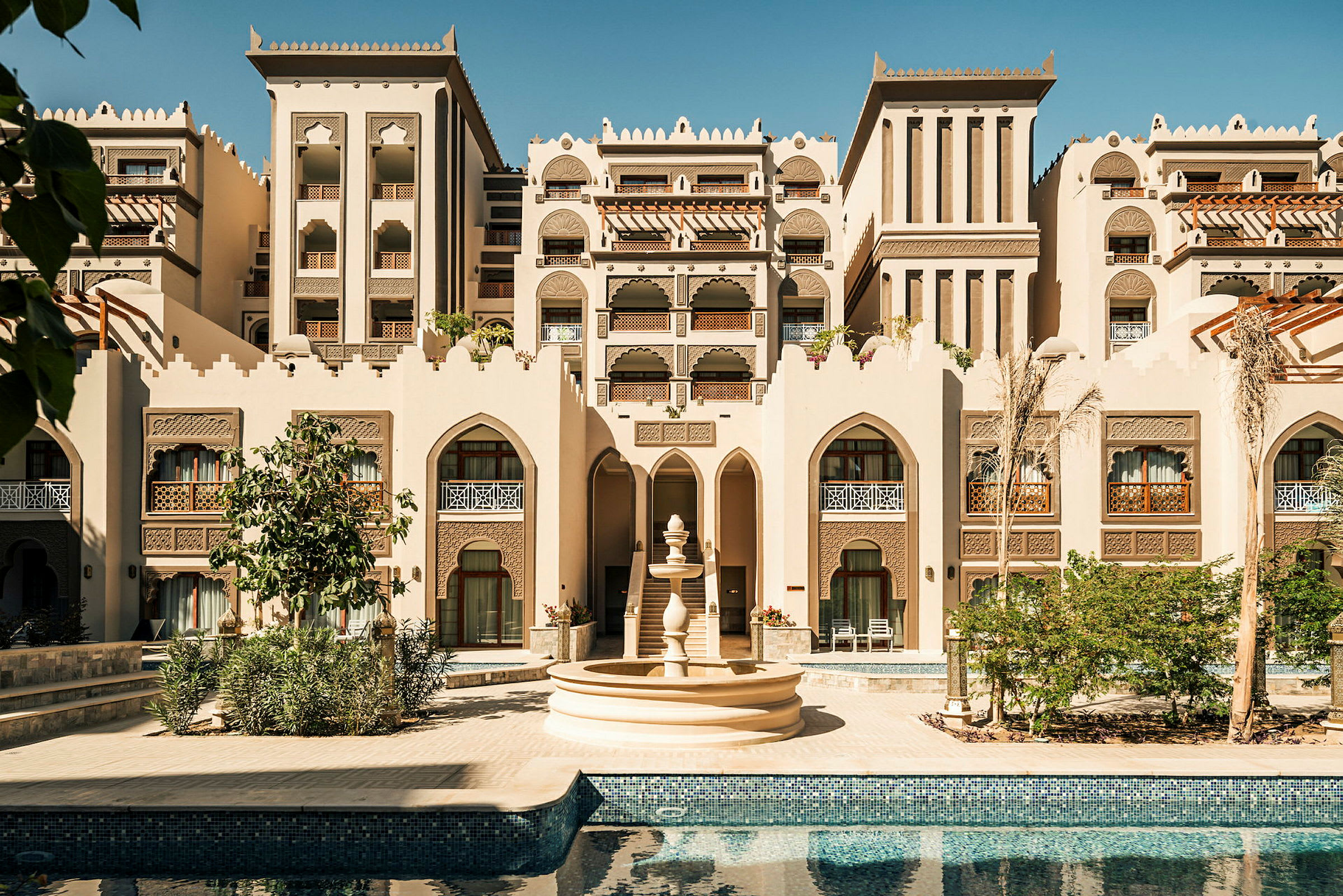 En bygning i arabisk arkitekturstil med en fontene og et basseng i forgrunnen. (AI-generert tekst)