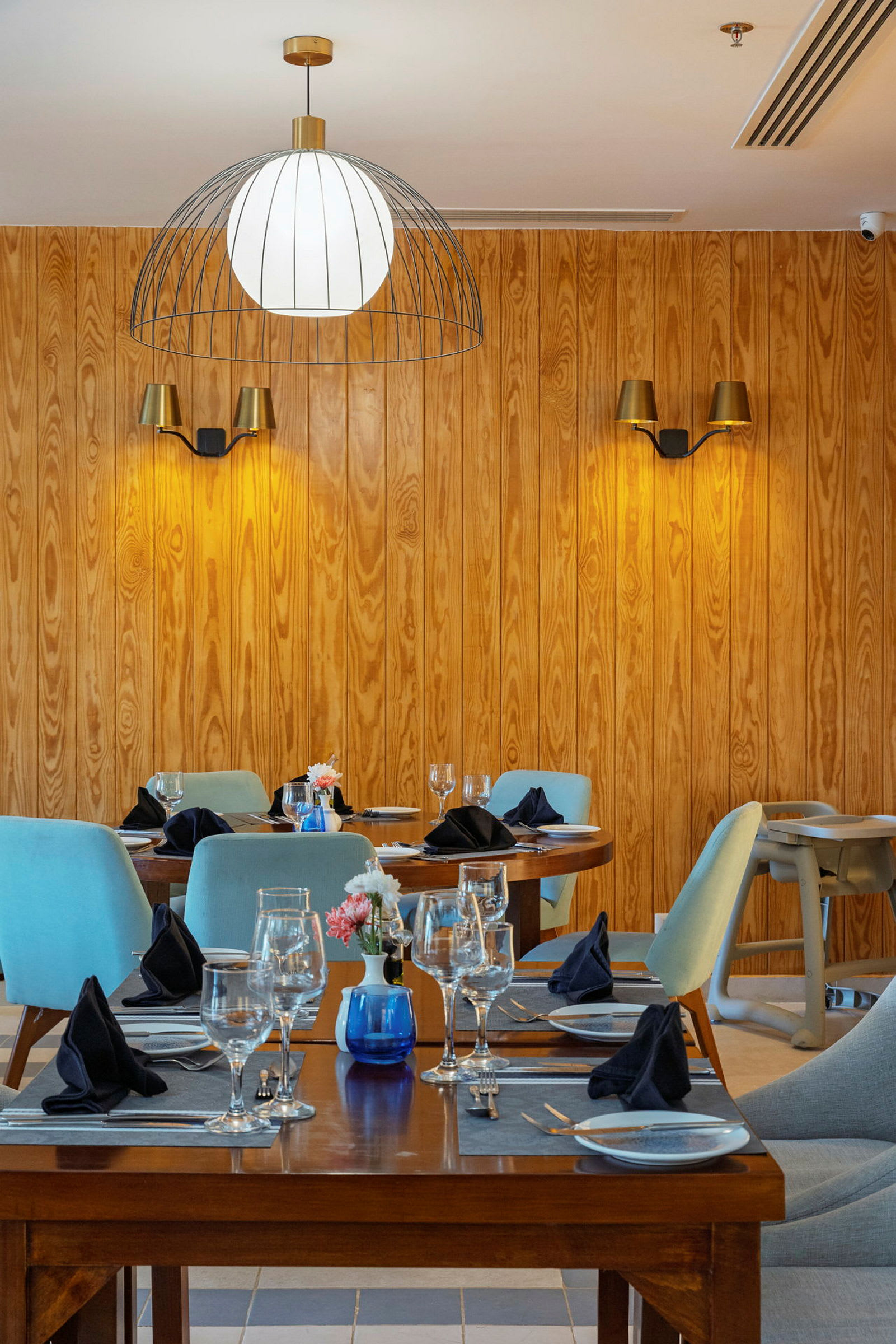 Interiør av en restaurant med trevegger, dekkede bord og stoler. (AI-generert tekst)