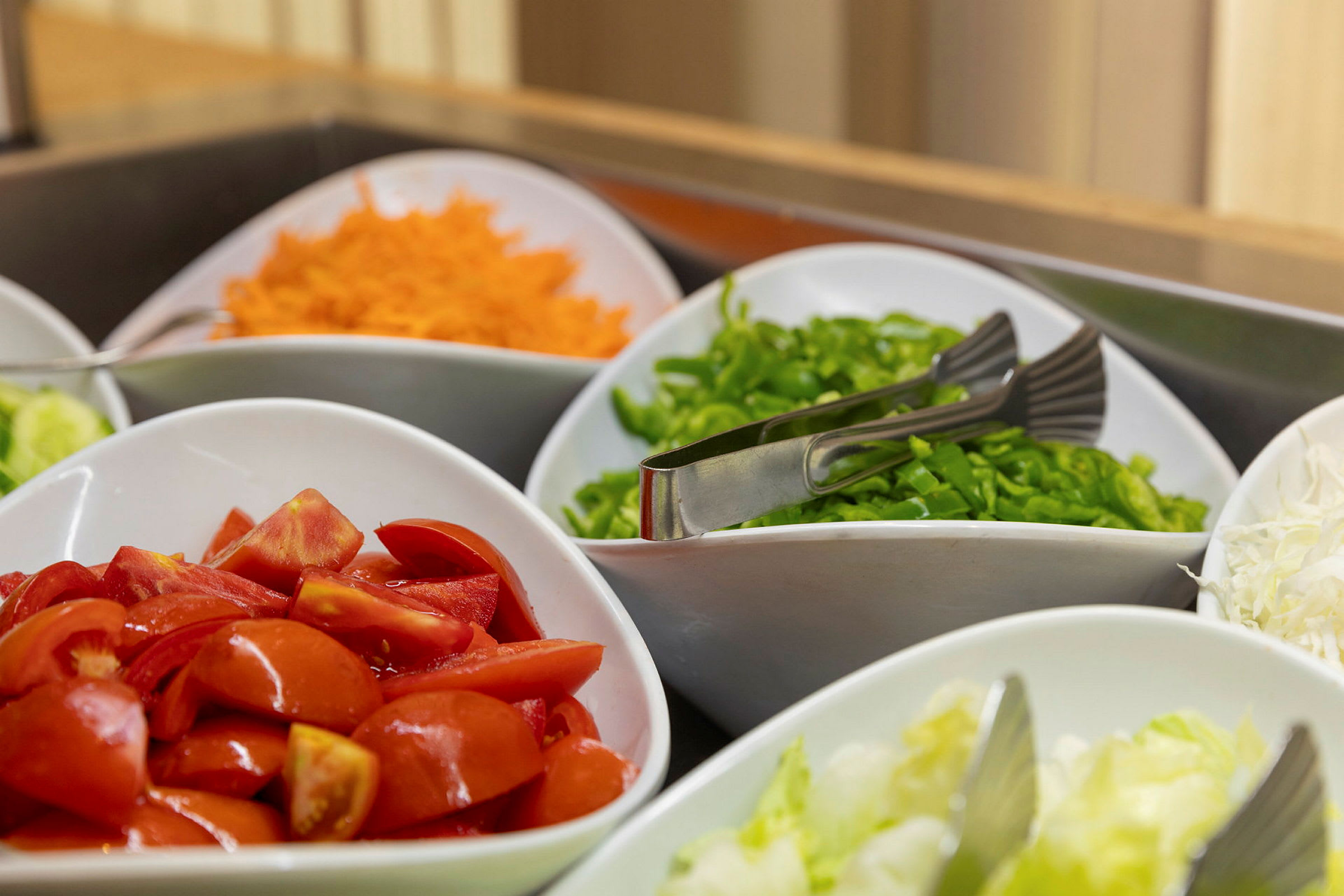 Friske grønnsaker oppstilt i boller, inkludert tomater, gulrøtter og paprika. (AI-generert tekst)