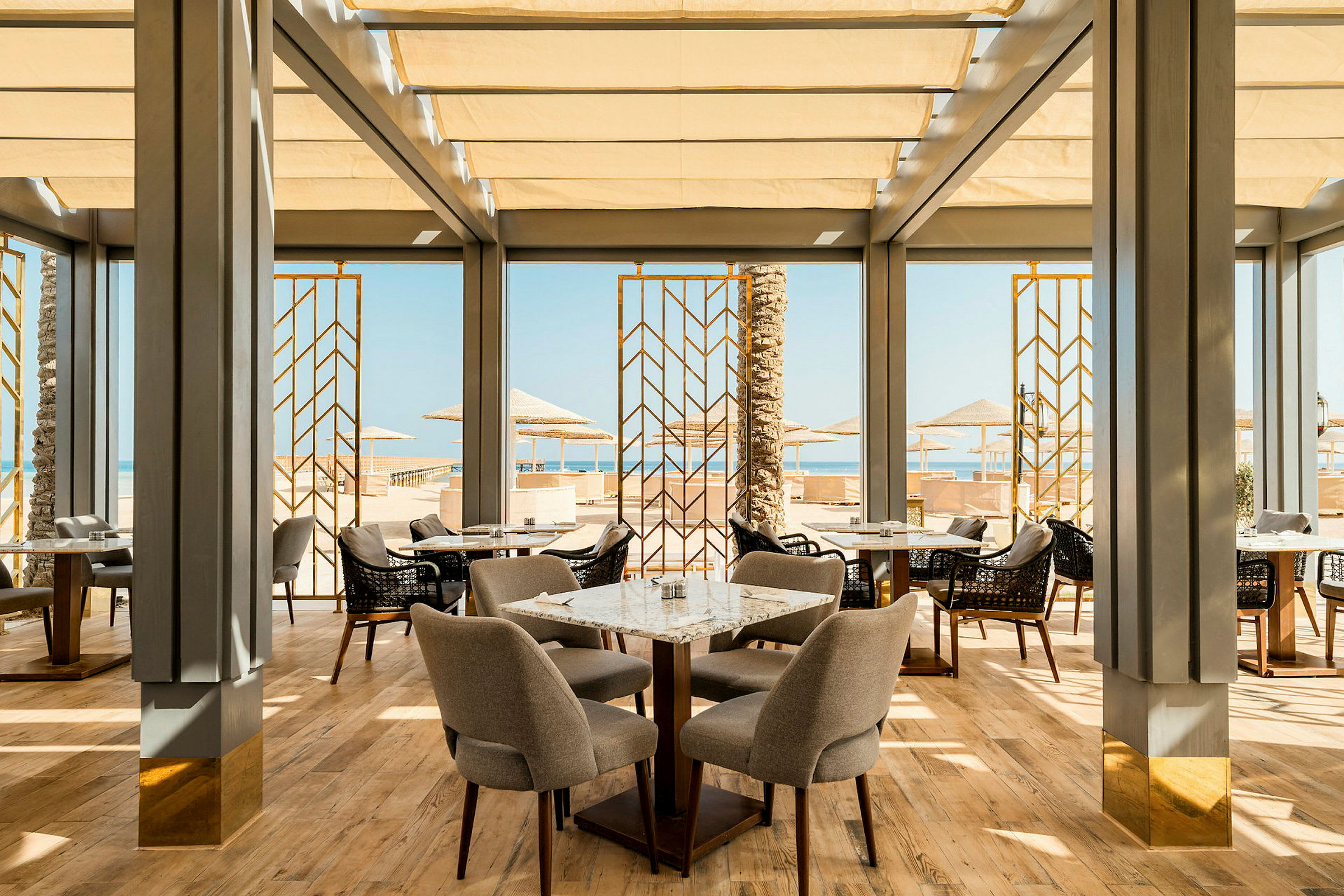 En elegant restaurant med store vinduer som vender ut mot stranden og havutsikten (AI-generert tekst)