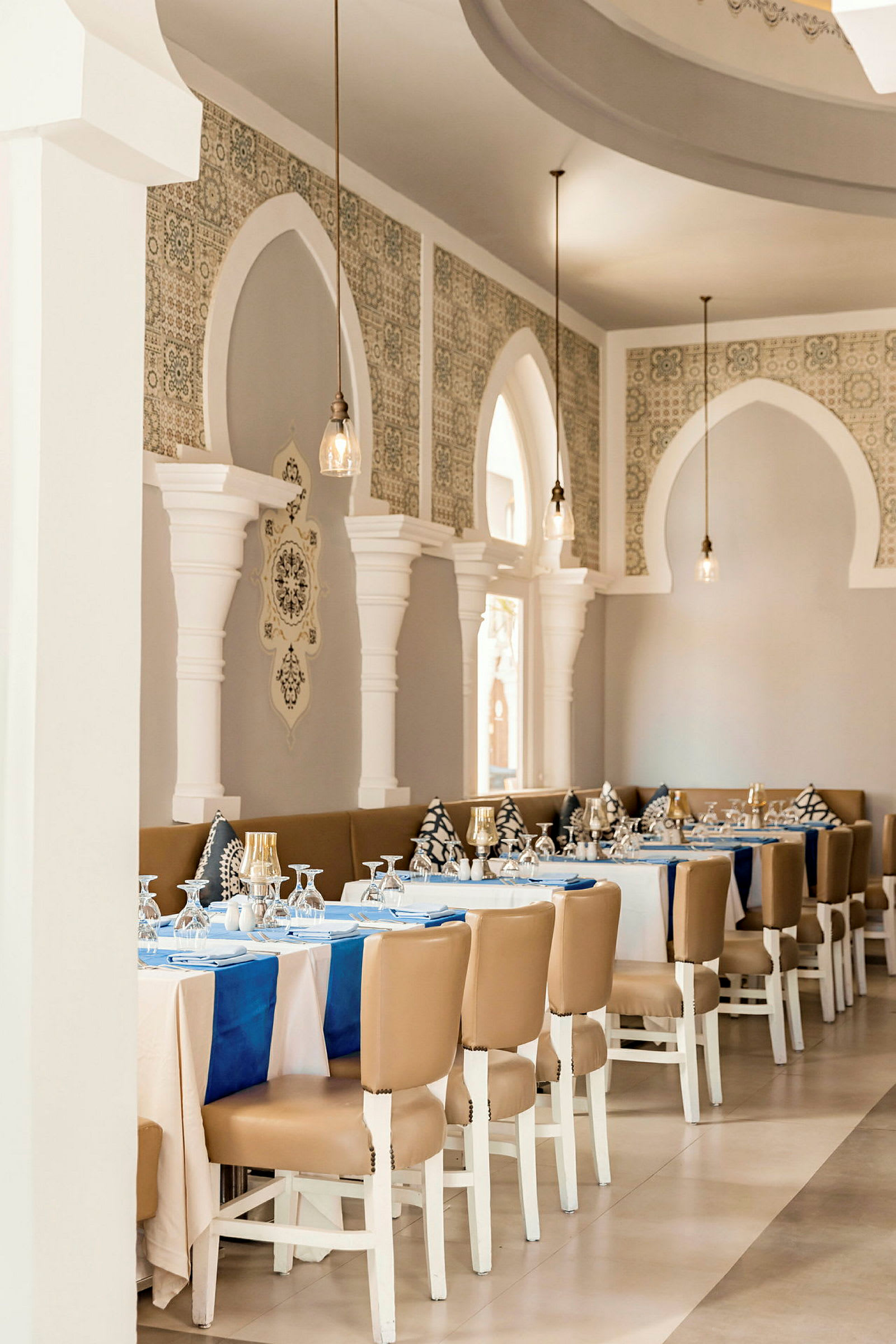 En elegant restaurant med dekkede bord, hvite vegger og dekorative buer. (AI-generert tekst)