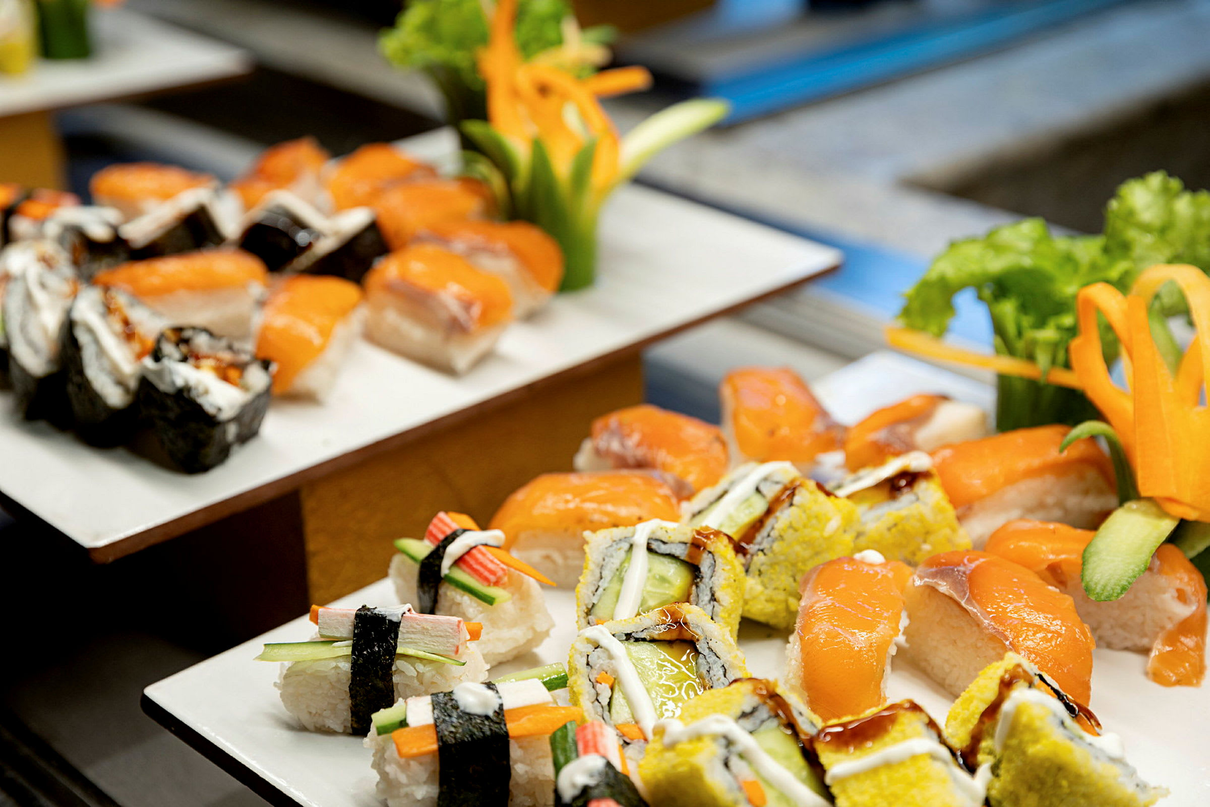 En tallerken med forskjellige typer sushi, inkludert nigiri med laks og maki-ruller, dekorert med friske grønnsaker. (AI-generert tekst)