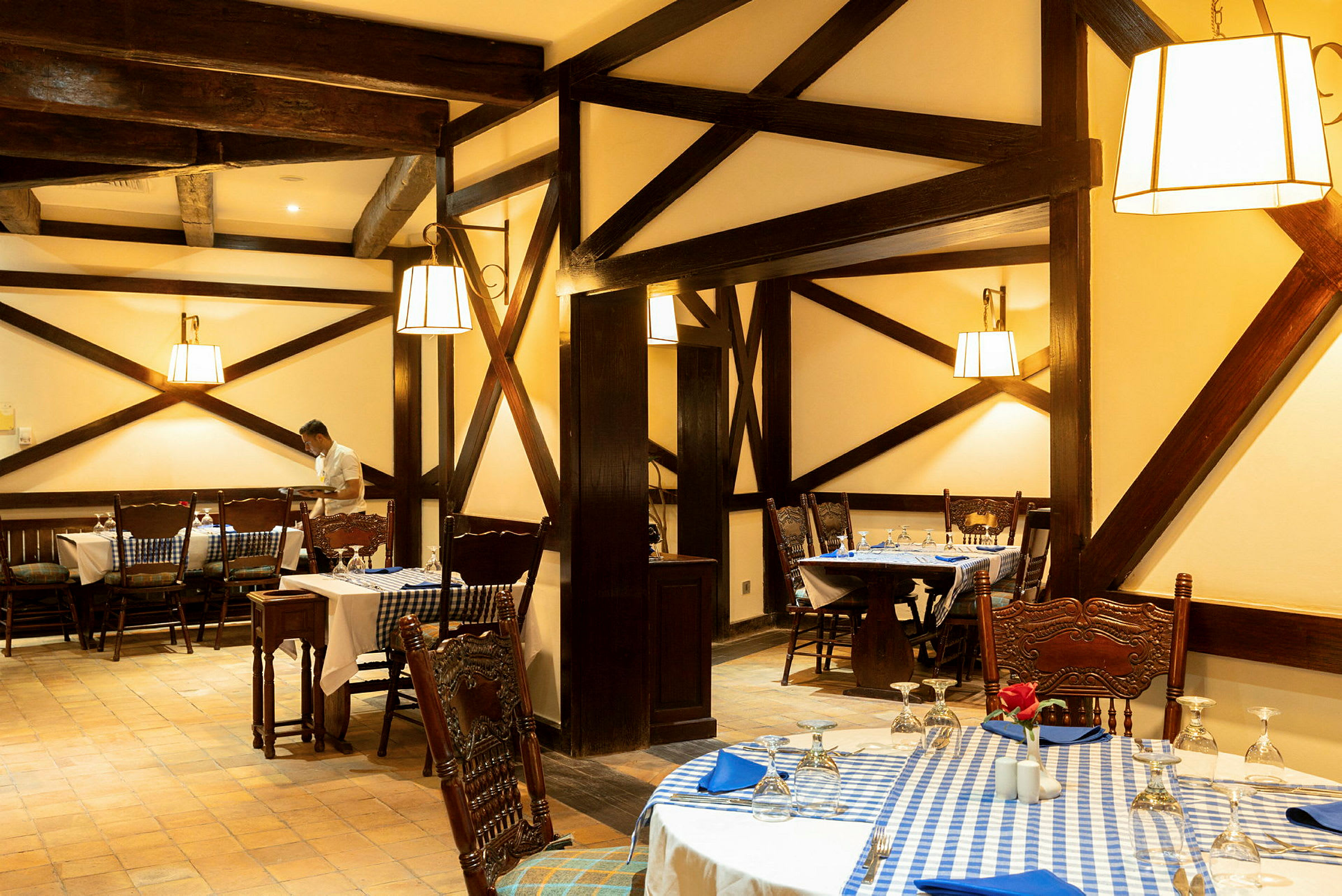 En restaurant med rustikk innredning og bord dekket med blå-hvite rutete duker. (AI-generert tekst)