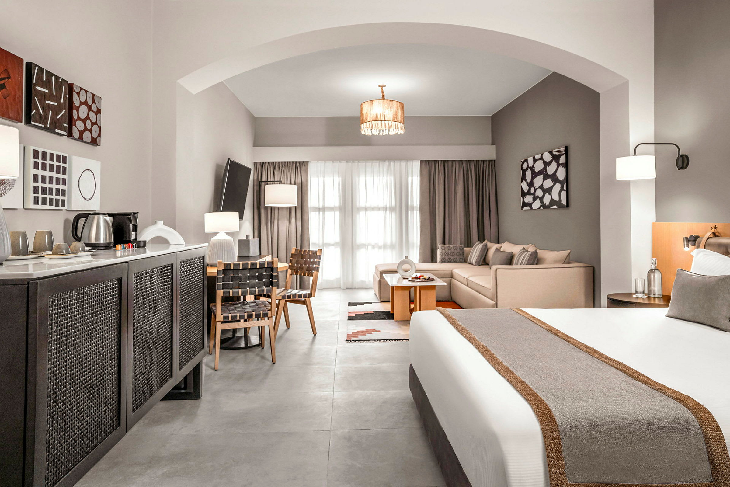 Et hotellrom med en seng, sittegruppe og spisebord, samt moderne interiør. (AI-generert tekst)