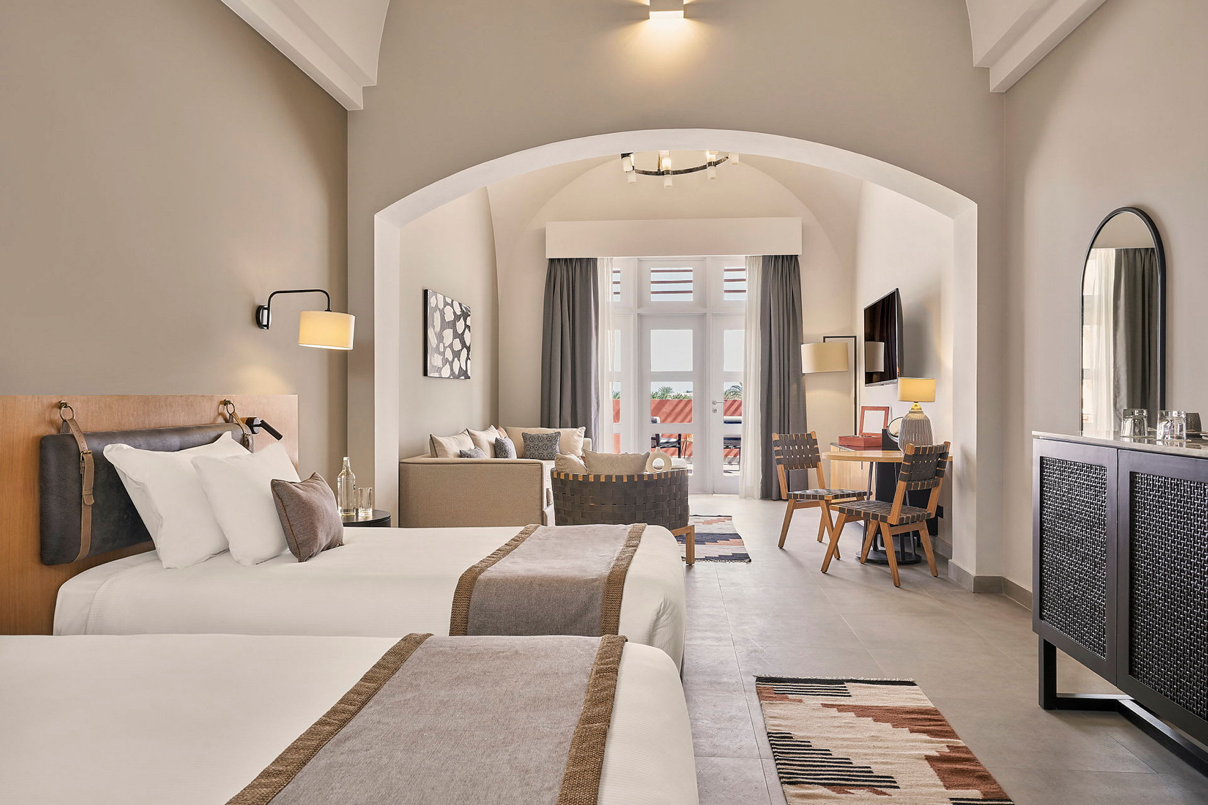 Hotellrom med to enkeltsenger, sittegruppe, skrivebord og balkong. (AI-generert tekst)