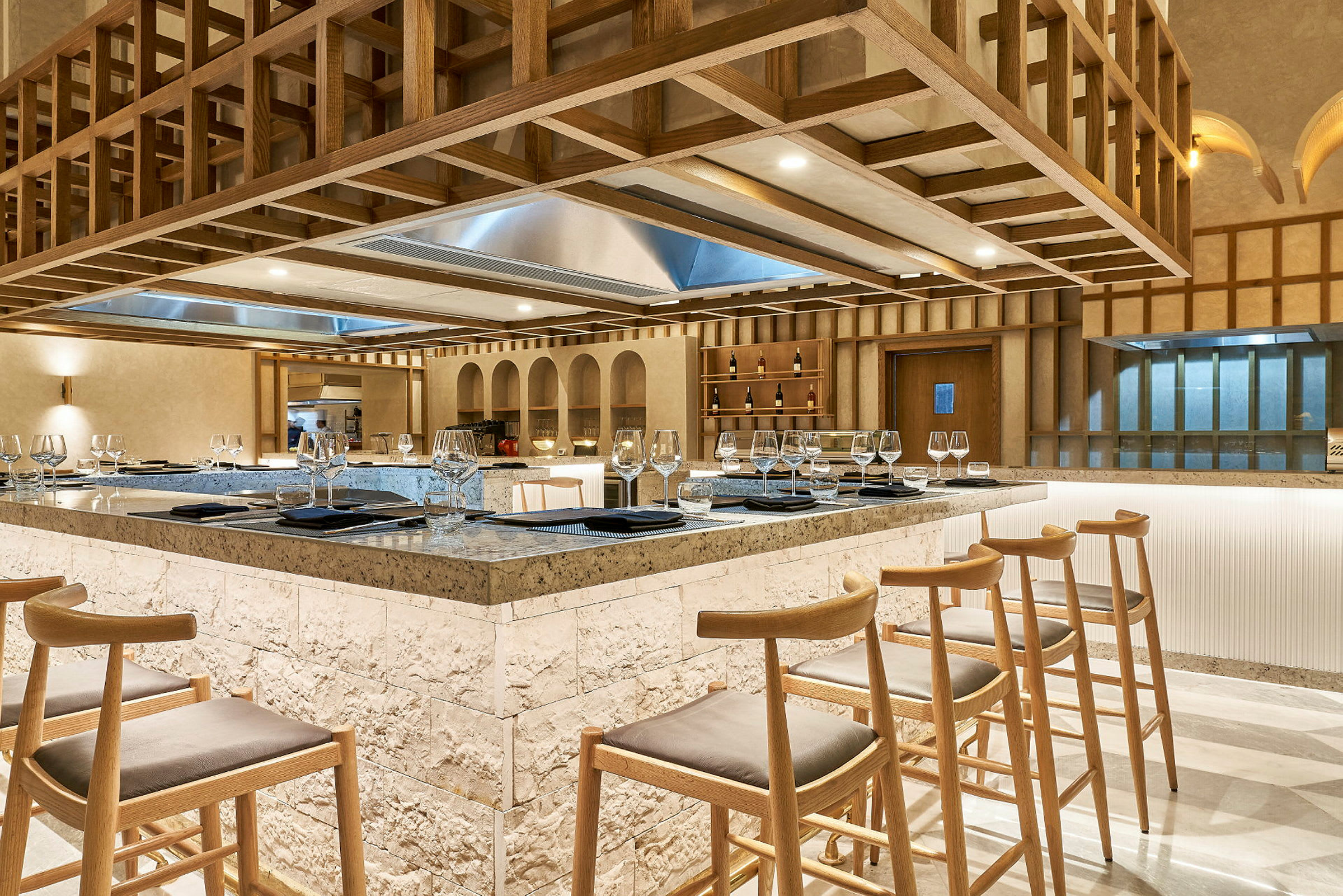 En elegant restaurant med en sentral bardisk omgitt av høye trestoler. (AI-generert tekst)
