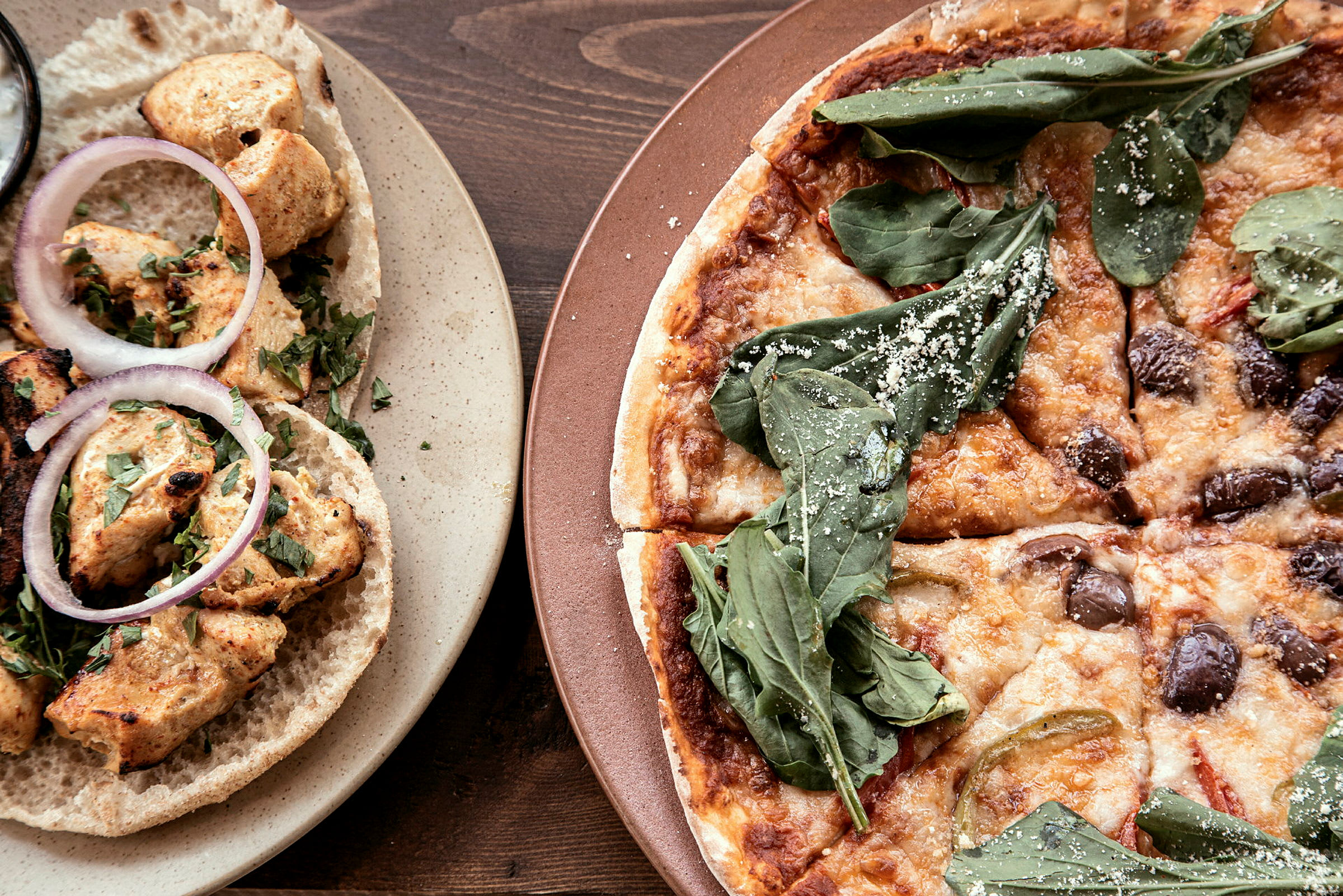 Matbilde som viser kyllingwraps og pizza. (AI-generert tekst)