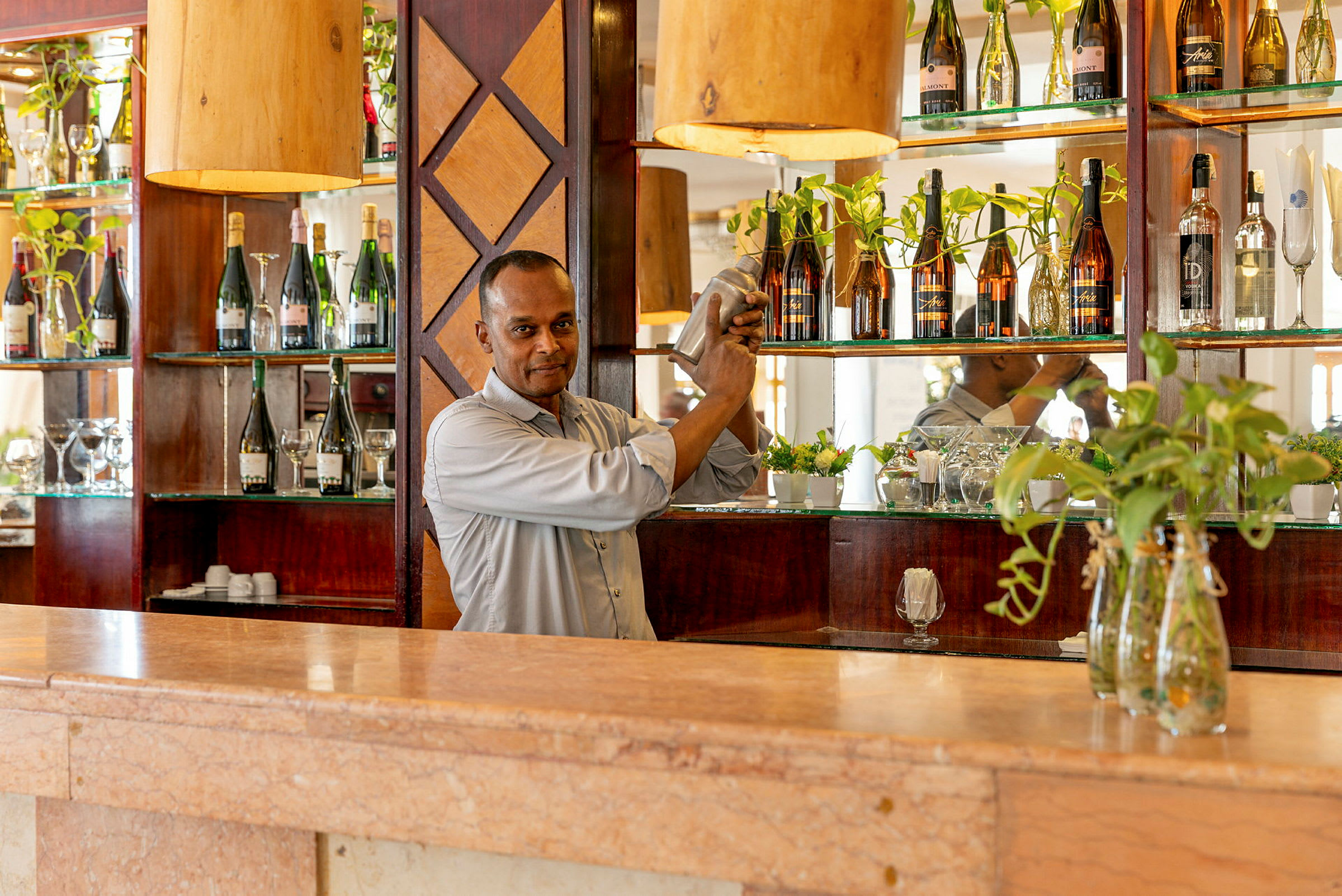 En bartender rister en cocktail bak en bardisk med flasker og dekorasjoner. (AI-generert tekst)