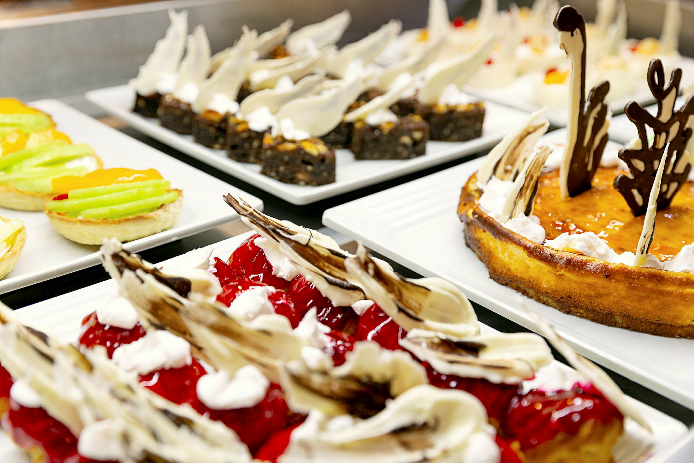 Bilde av ulike desserter lagt opp på tallerkener på en buffet. (AI-generert tekst)