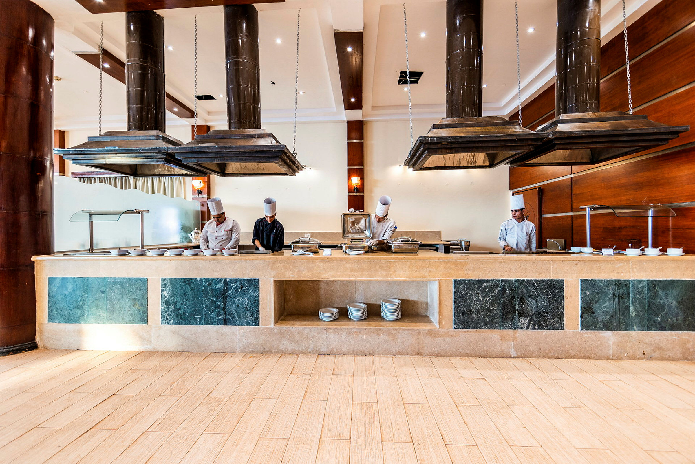 En hotellrestaurant med en buffédisk og kjøkkenutstyr under store ventilatorer. (AI-generert tekst)