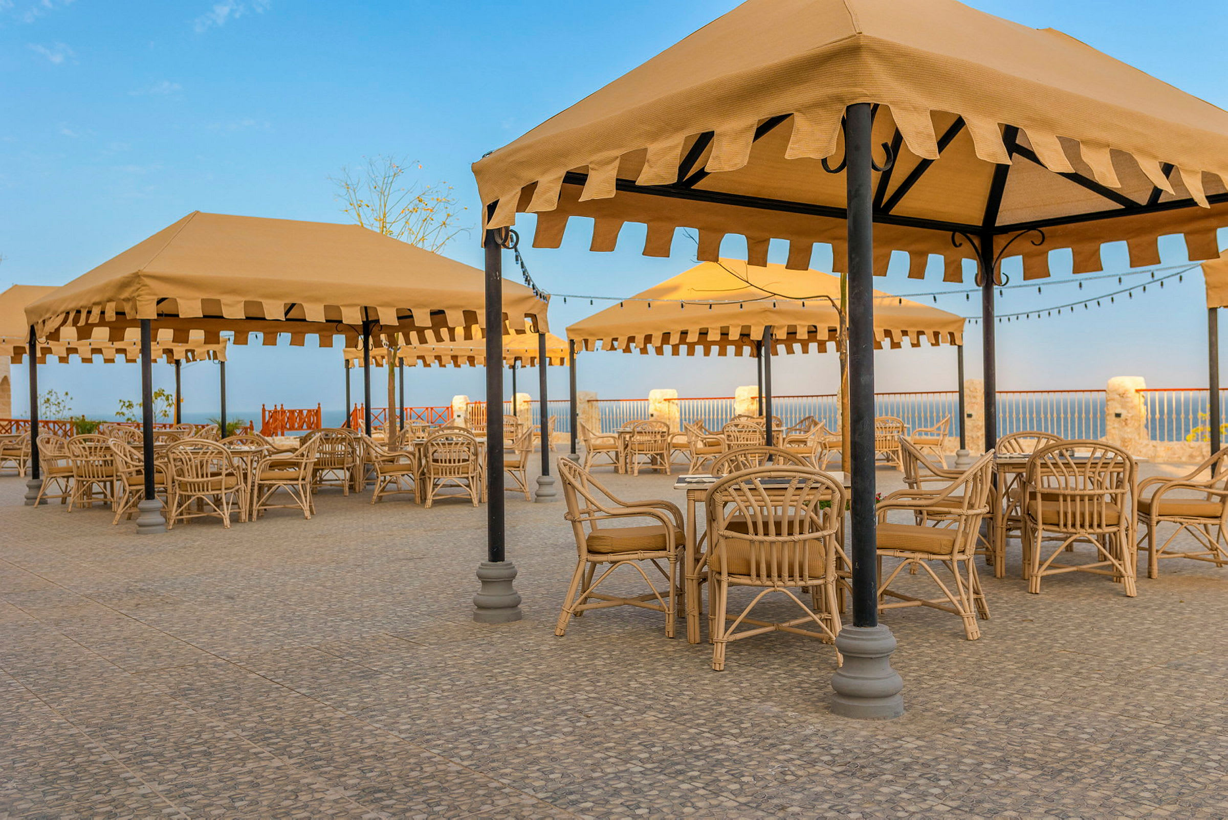 Utendørsområde med parasoller og kurvmøbler. (AI-generert tekst)