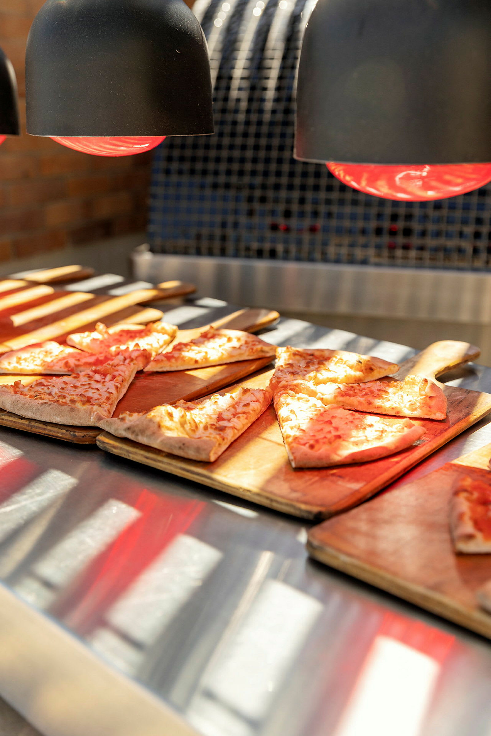 Pizza på skjærebrett under varmelamper. (AI-generert tekst)