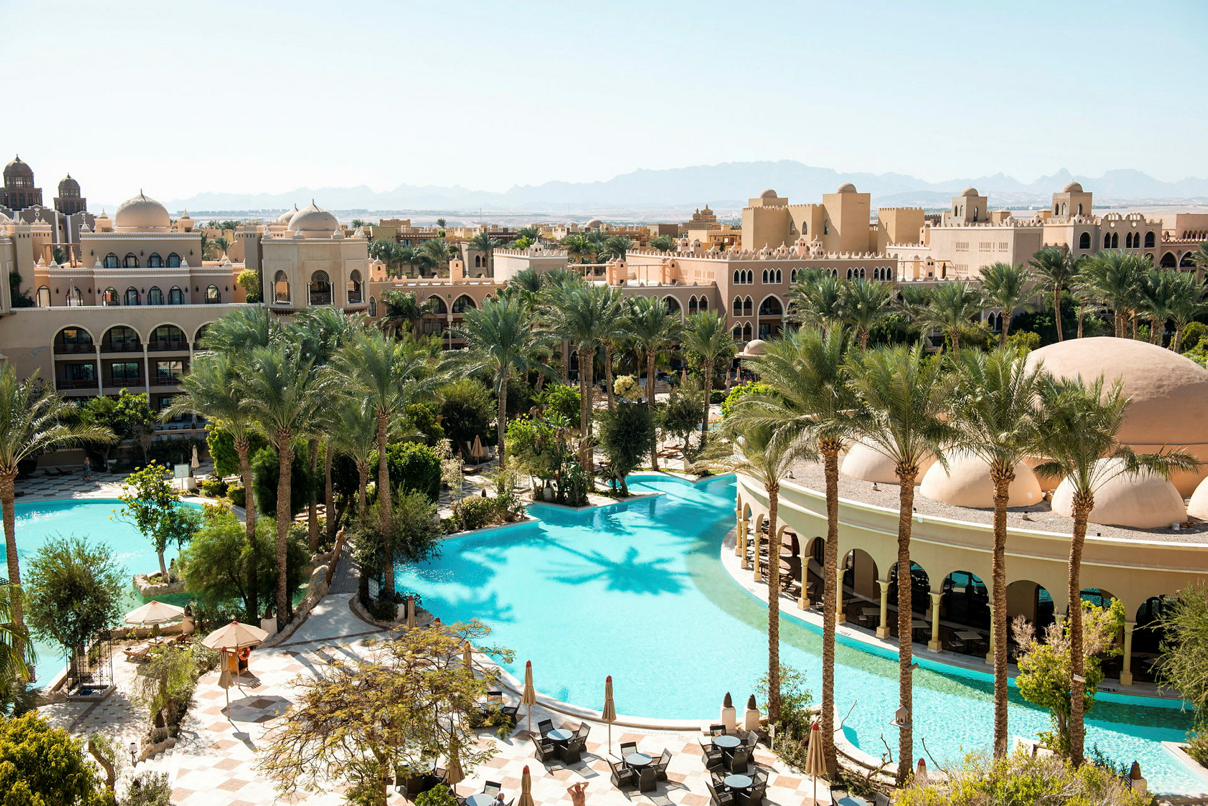 Et hotellområde med basseng, palmer og bygninger i arabisk arkitektur. (AI-generert tekst)