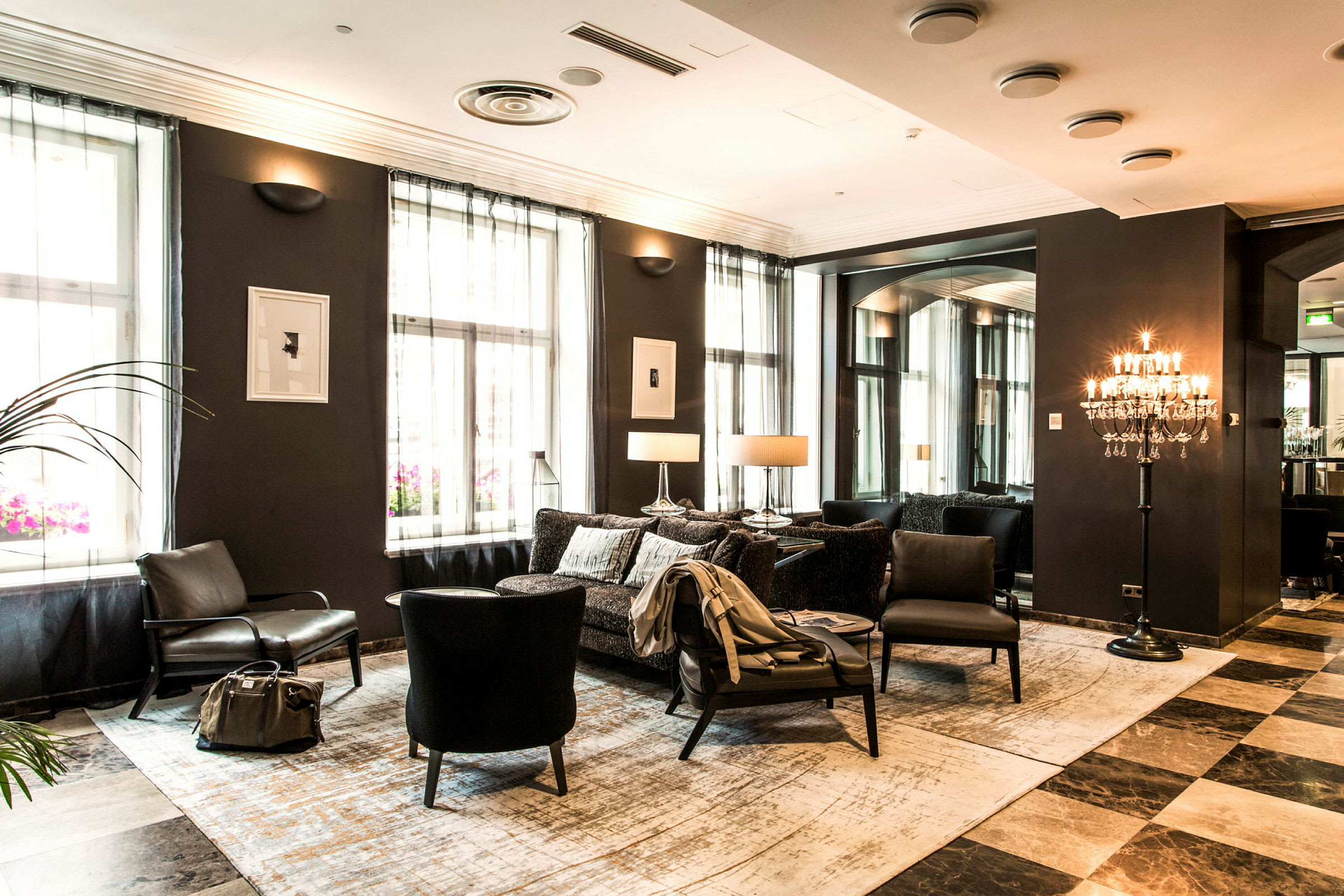 Et elegant hotellrom med sittemøbler, vegglamper og vinduer med lyse gardiner. (AI-generert tekst)