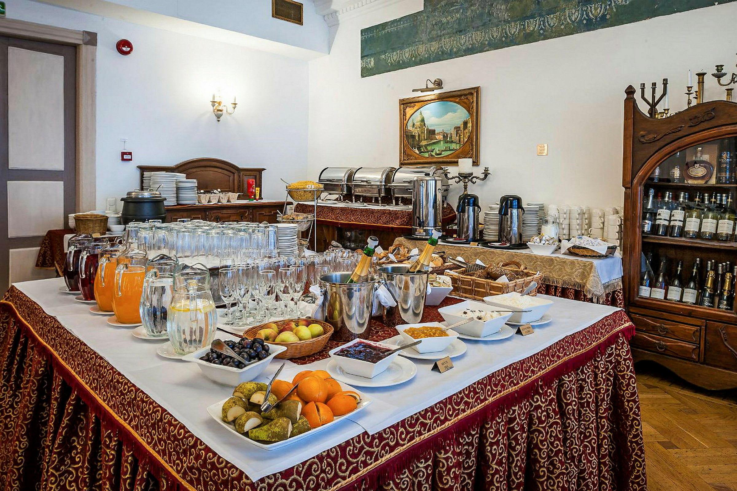 Et buffébord med ulike drikker, frukt og småretter satt opp i en elegant restaurant. (AI-generert tekst)
