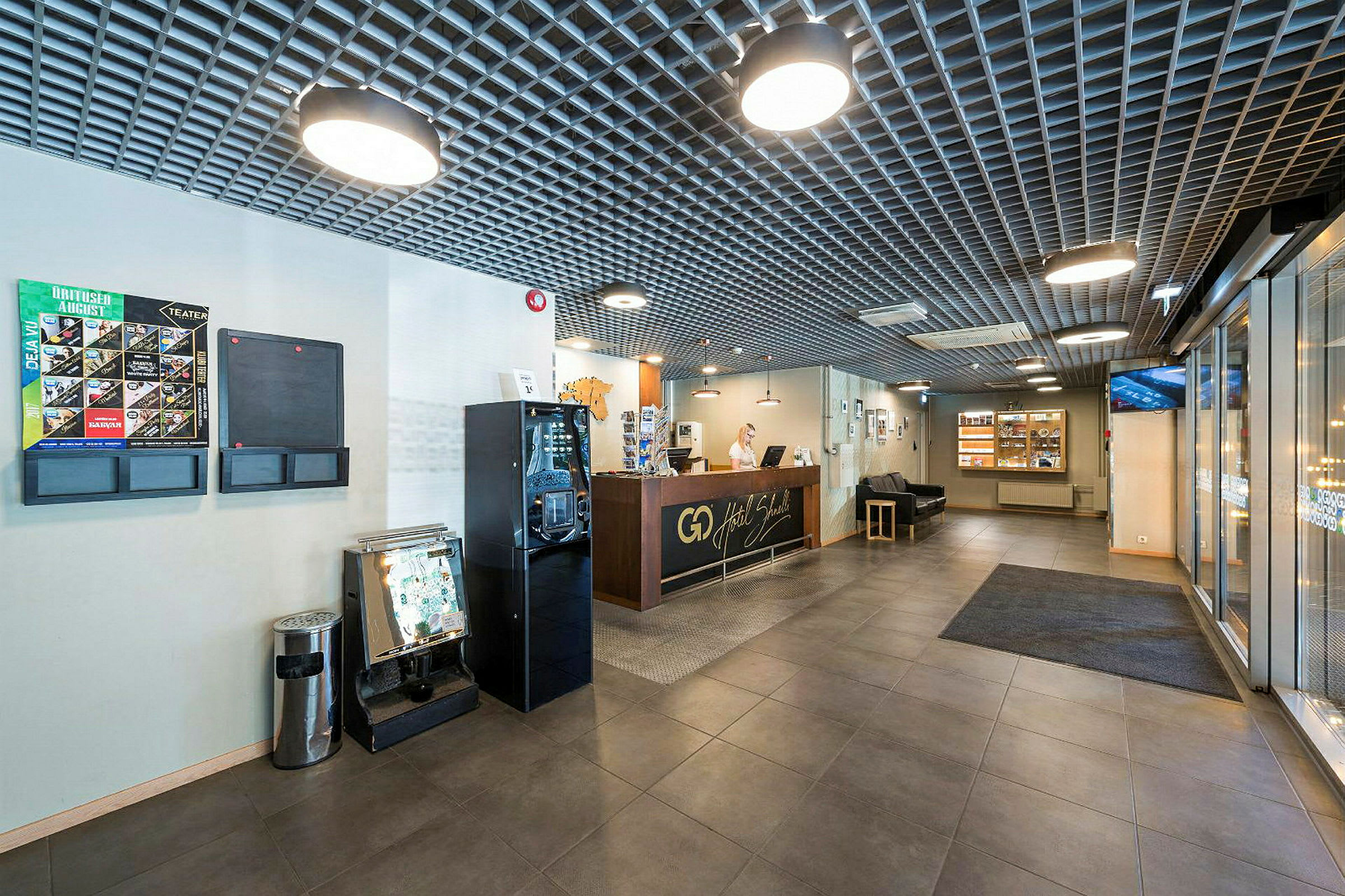 Resepsjon på et hotell med sittegruppe og brosjyrestativ. (AI-generert tekst)