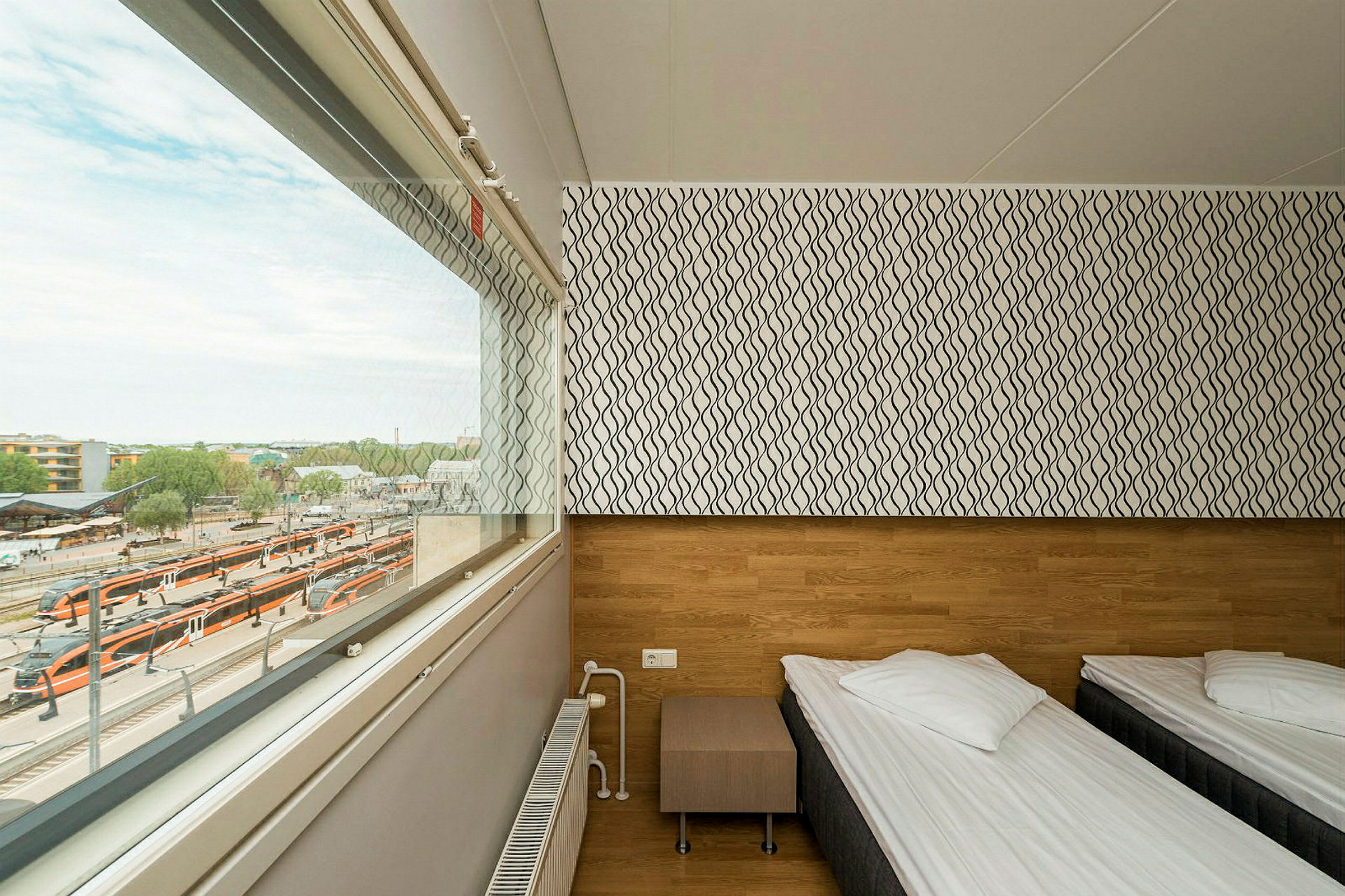 Et enkelt hotellrom med to enkeltsenger, et vindu med utsikt over en togstasjon. (AI-generert tekst)
