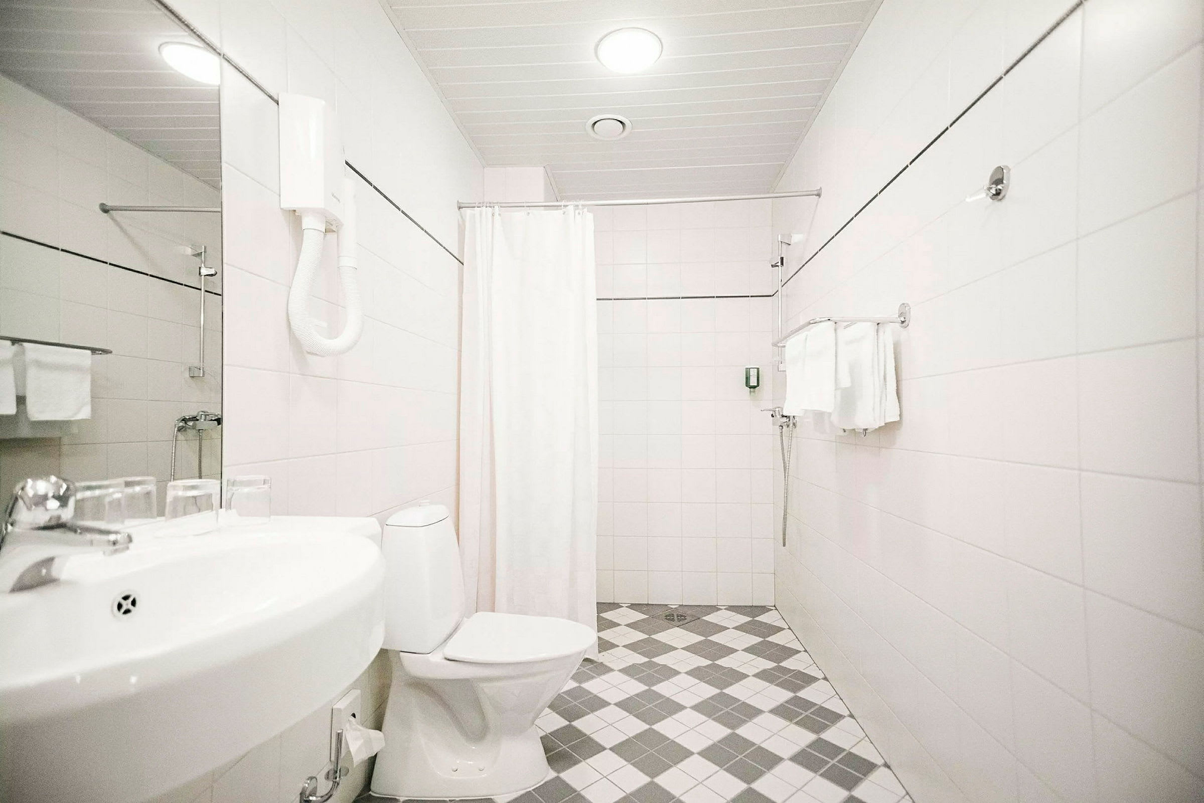 Hotellbad med toalett, vask og dusj. (AI-generert tekst)