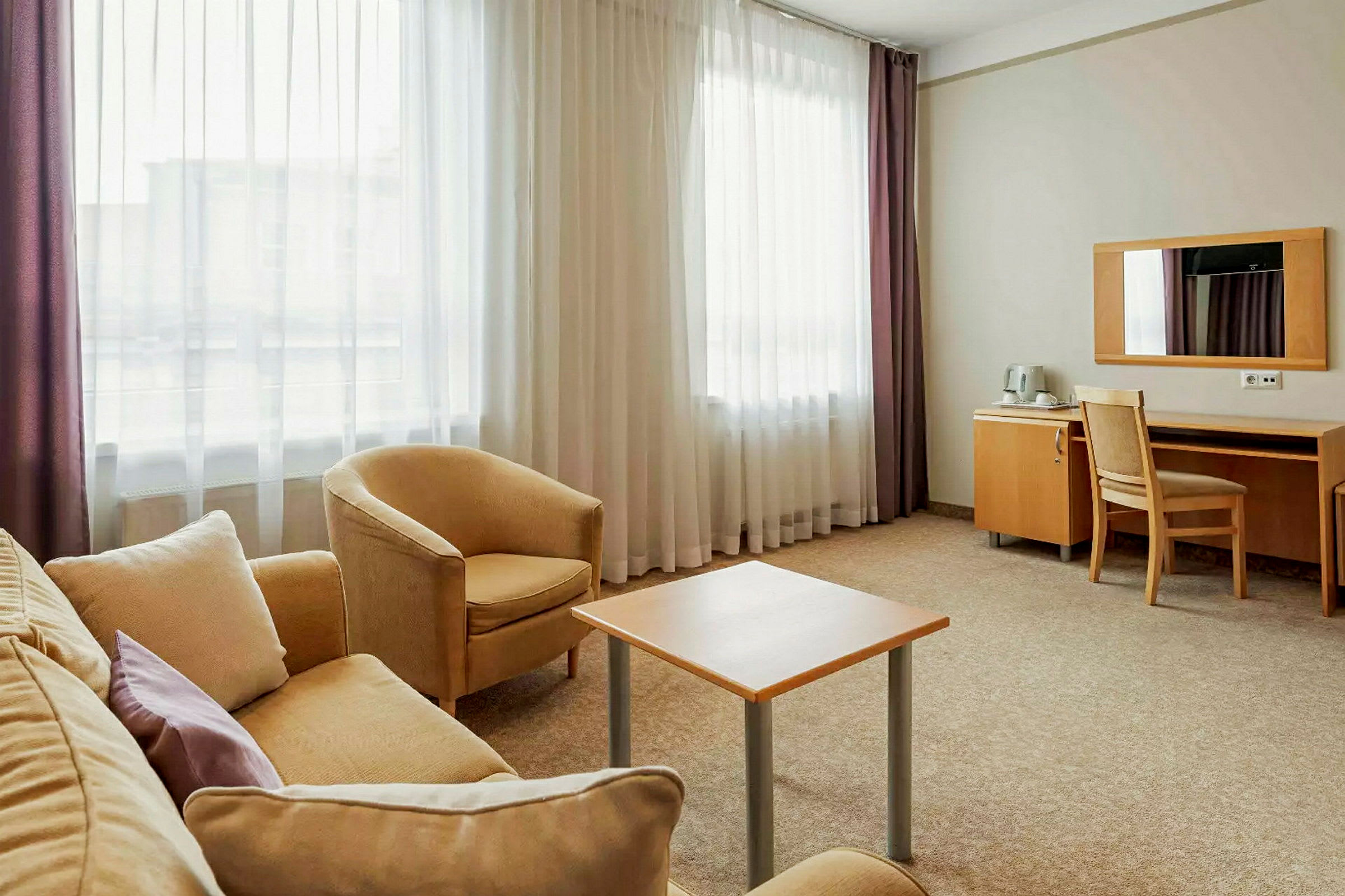 Et hotellrom med sittegruppe og skrivebord. (AI-generert tekst)