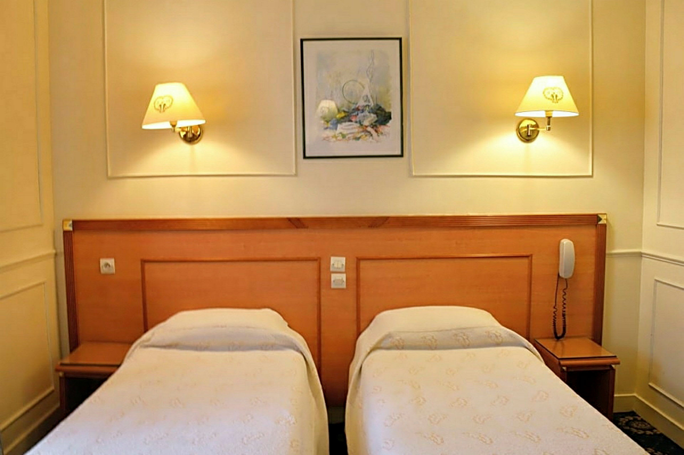 Et hotellrom med to enkeltsenger og vegglamper. (AI-generert tekst)